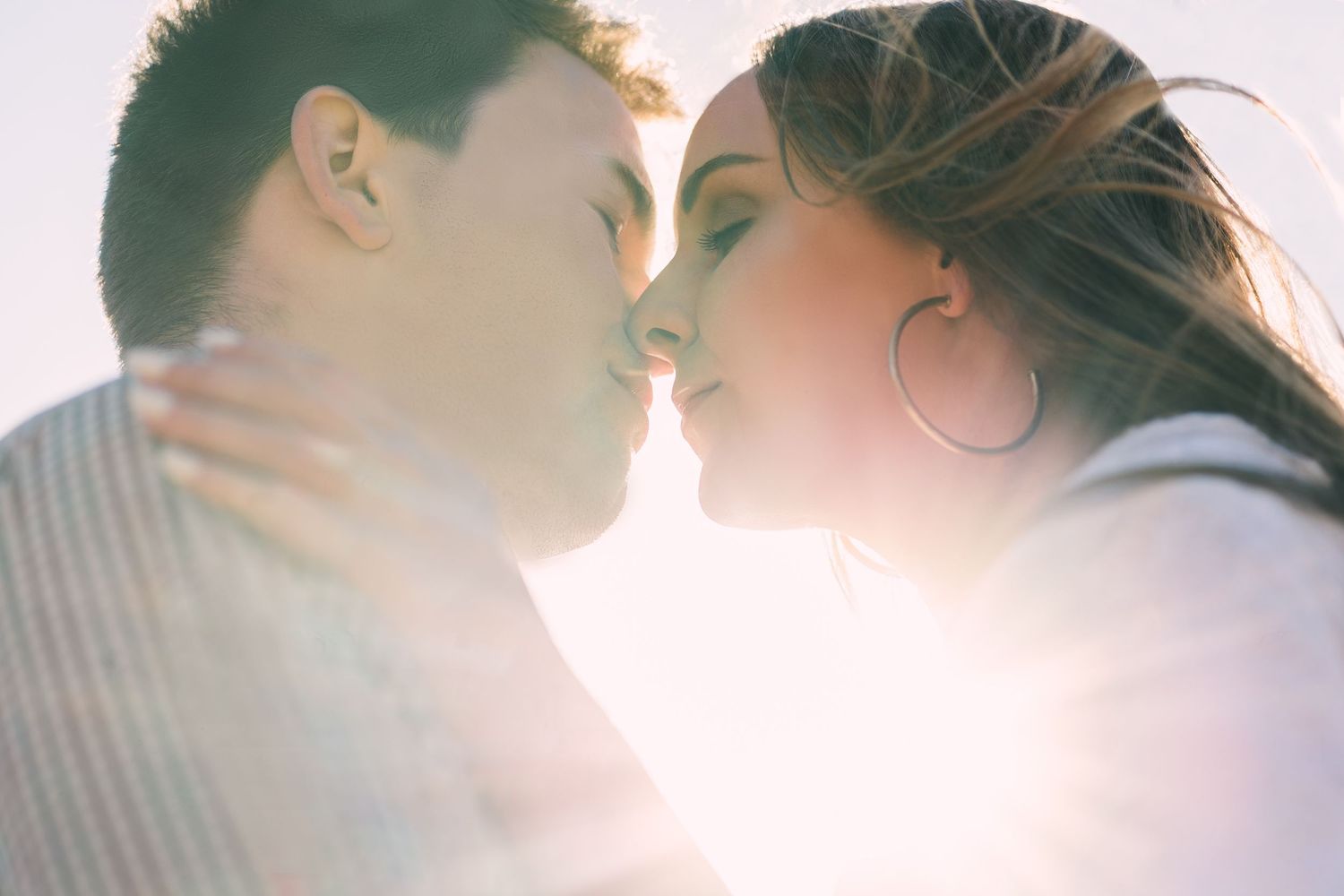 Close-up of couple nose-to-nose framed by golden hour light