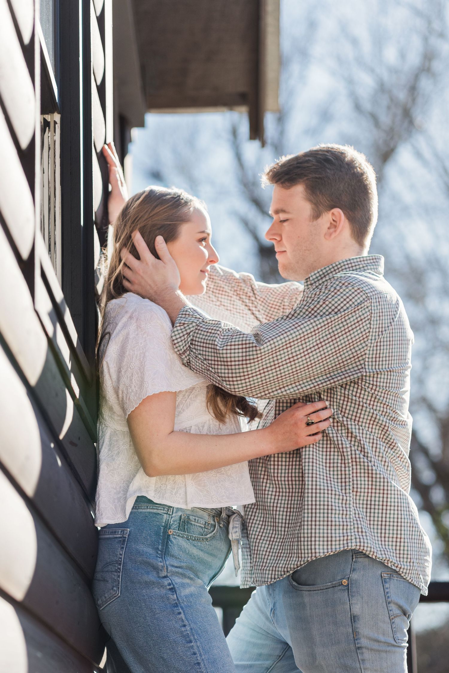 Man standing face to face with his fiancee, running his hand through her long hair.