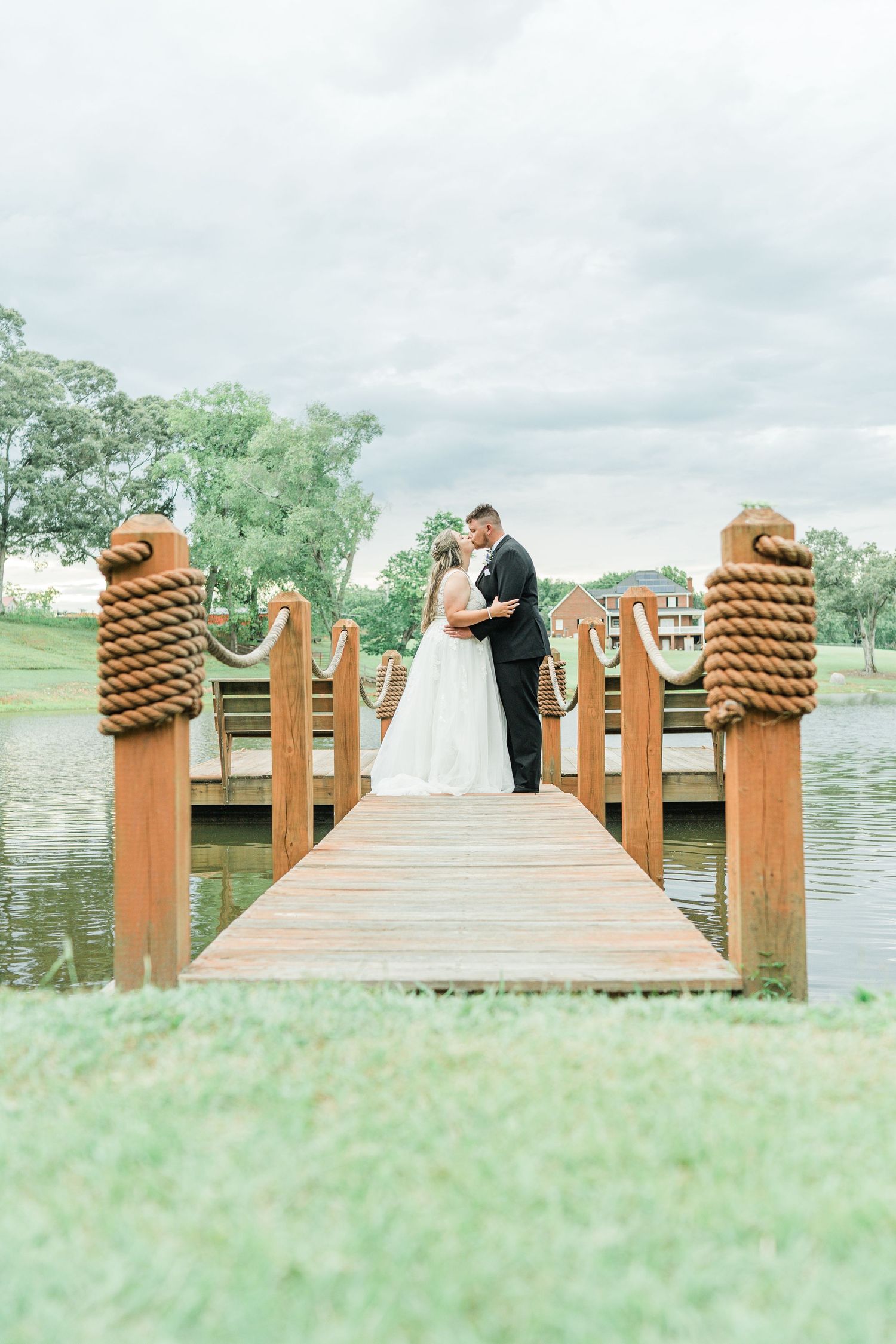 bride and groom kissing on a lake dock