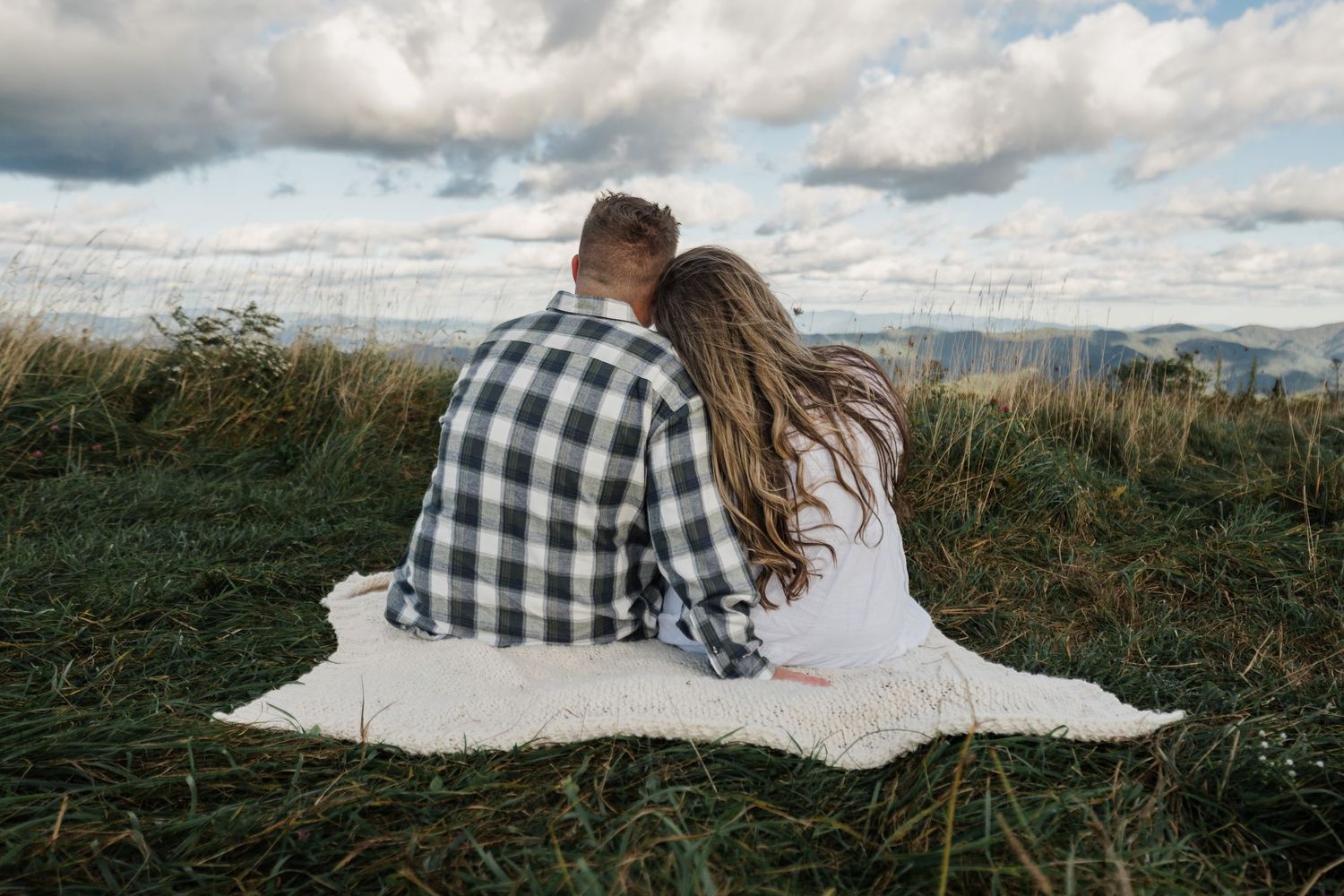 Man sits with his arm wrapped around his wife. They both look out over the Appalachian mountains.