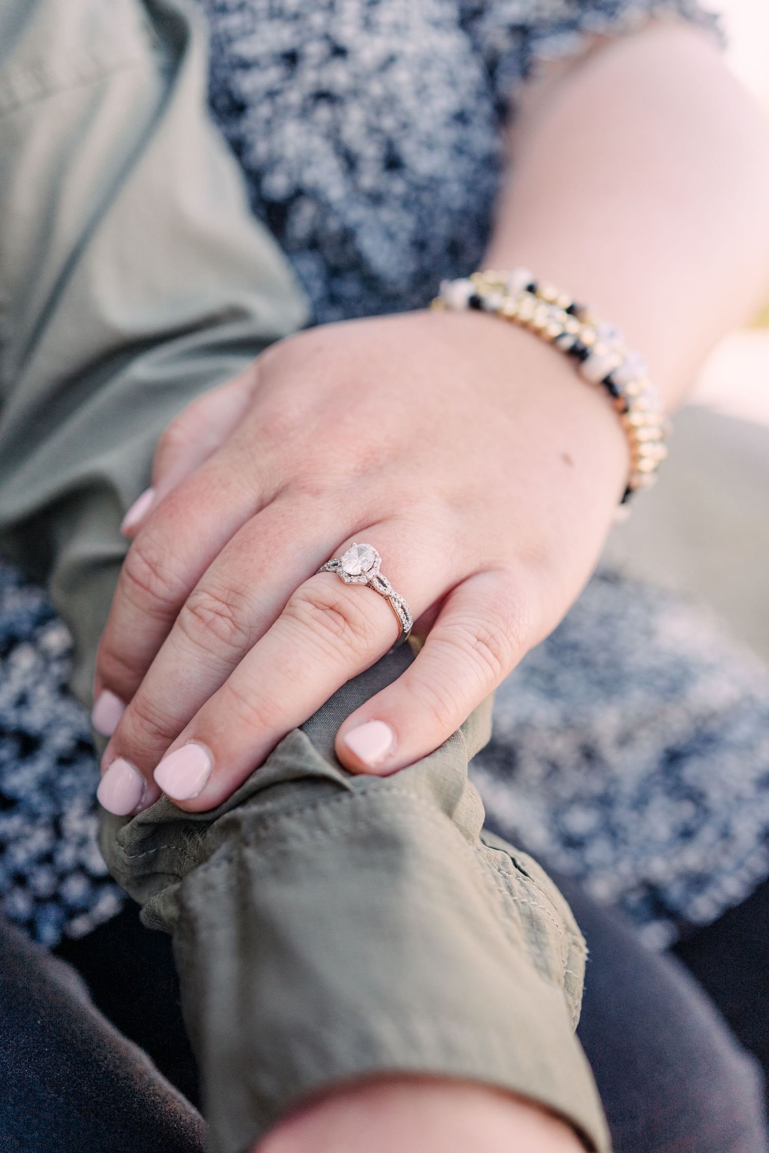 Bride's hand laying on groom's arm showing off her engagement ring