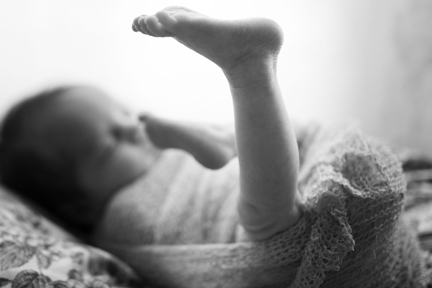 Close up of newborn foot wrapped in soft light.