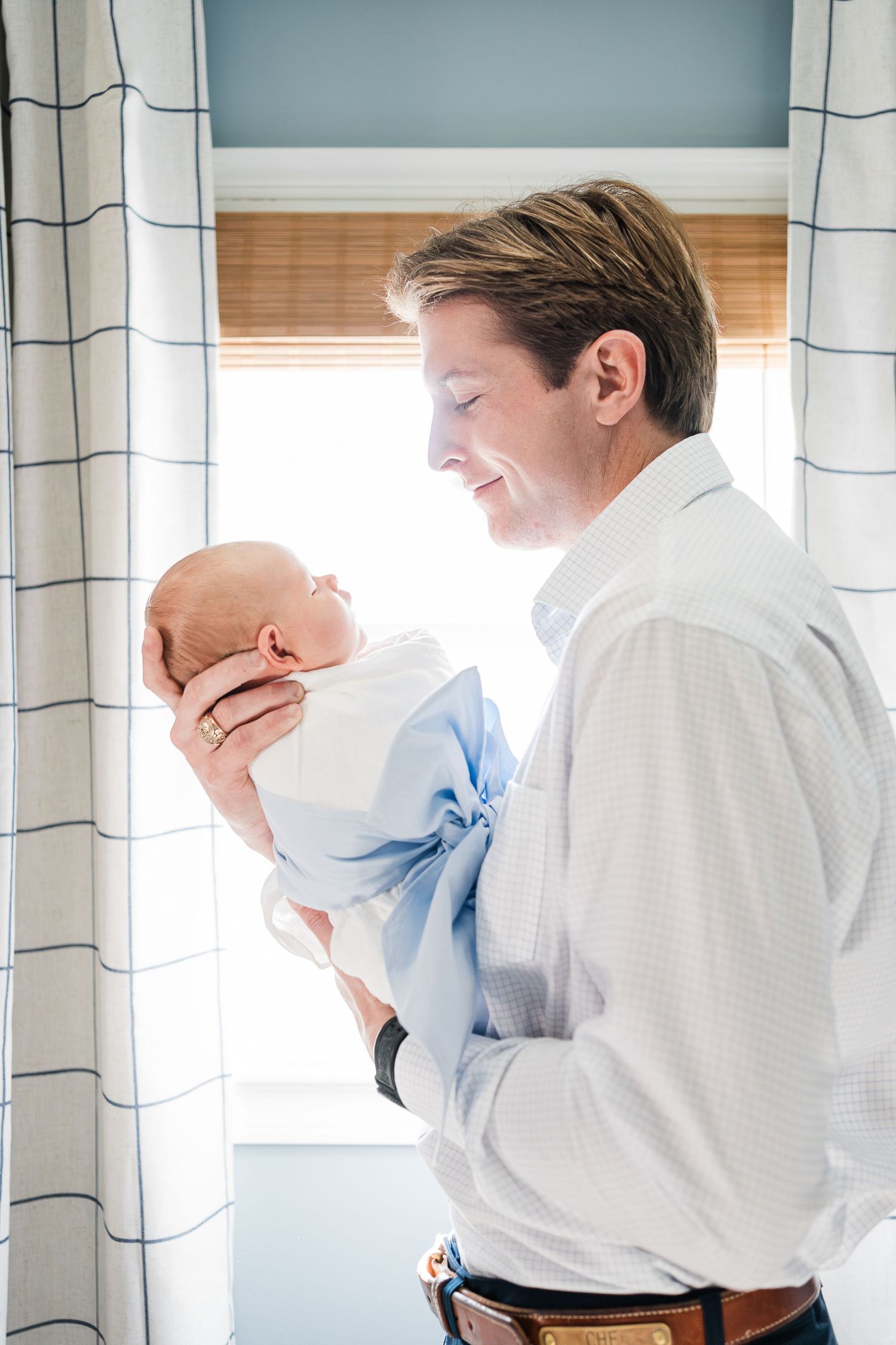 Dad proudly smiling down at newborn baby son