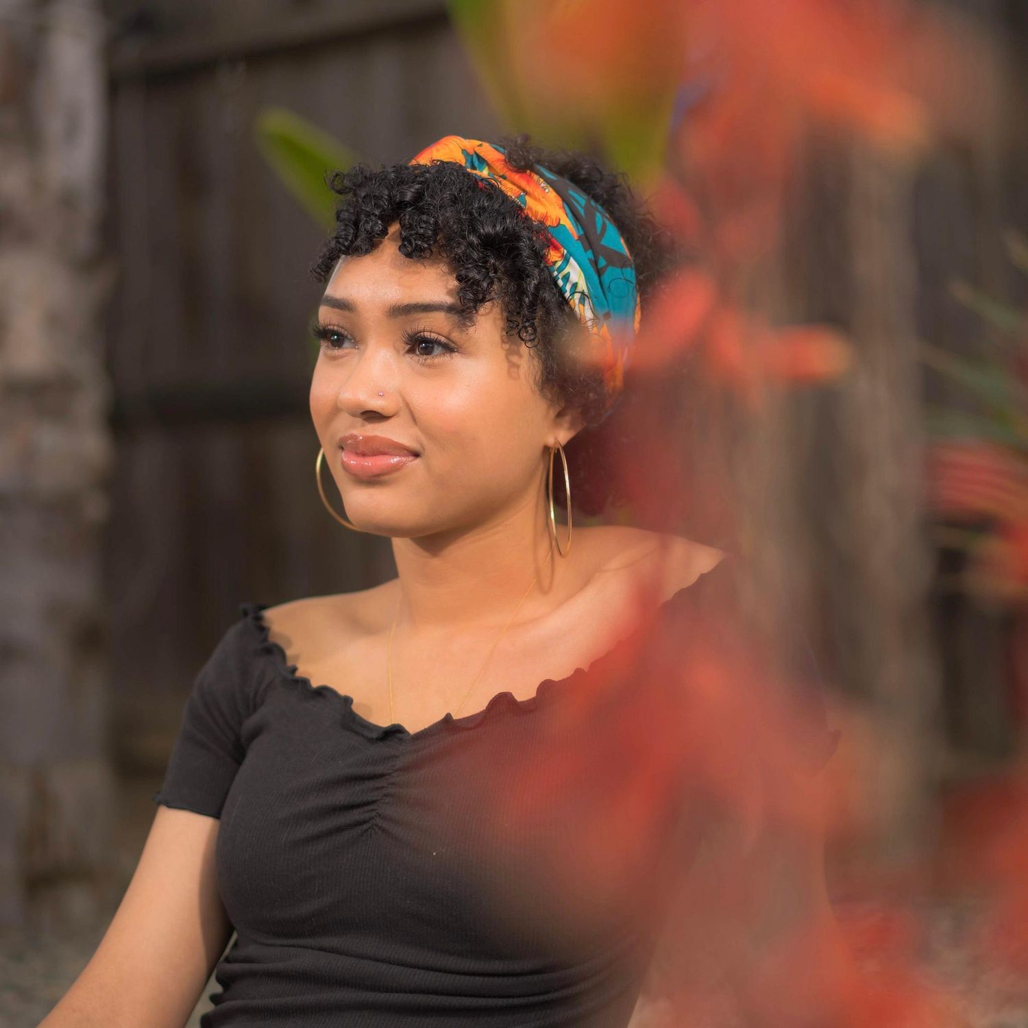 Portrait with natural curls against blurred orange autumn background.