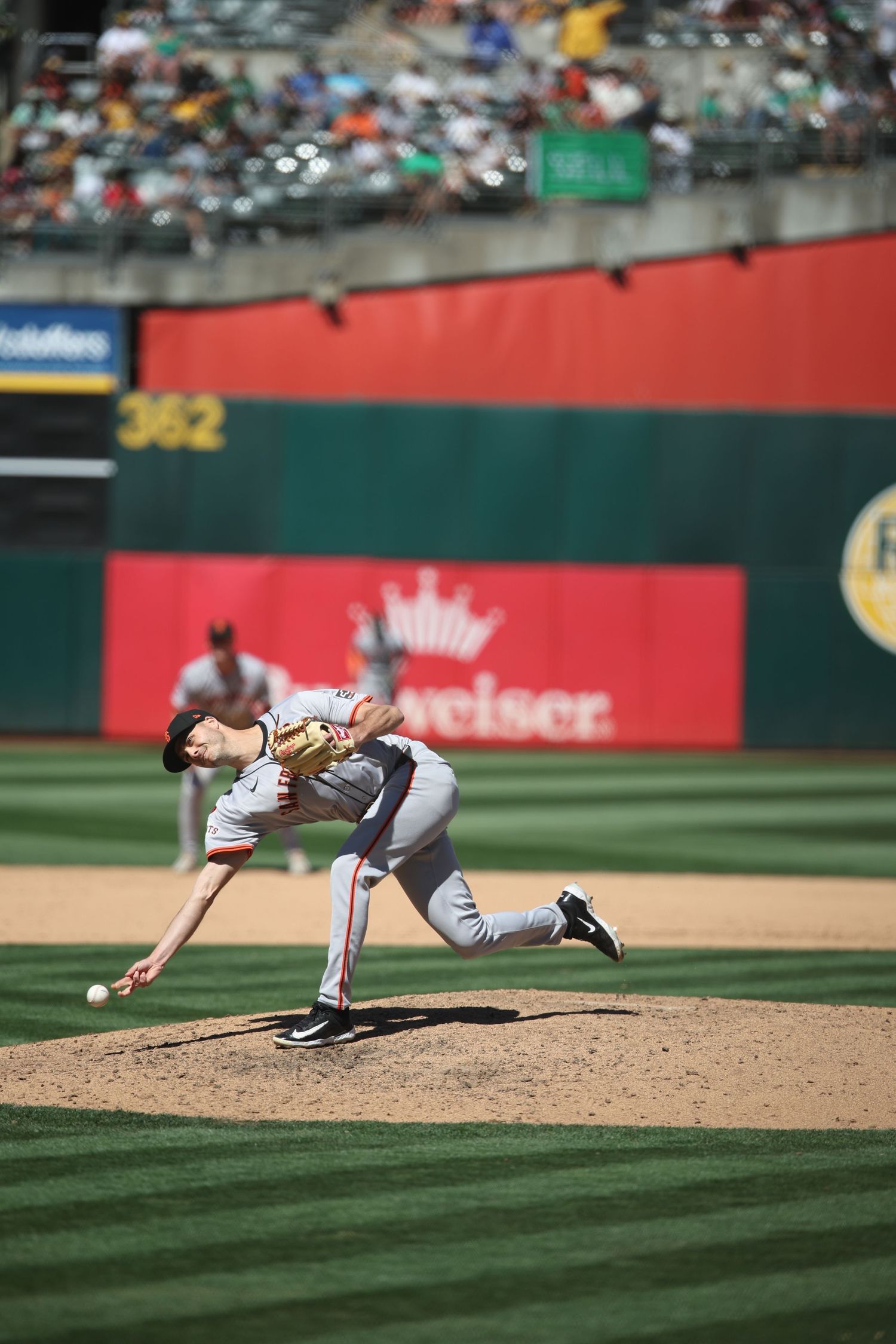 Baseball pitcher diving dramatically towards home plate during game play.