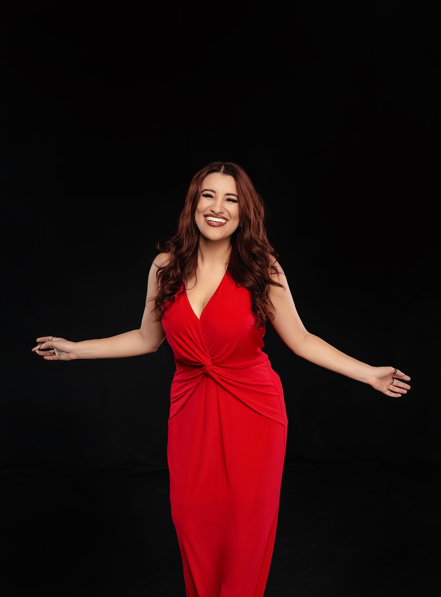 Person in red dress twirling and dancing joyfully against black backdrop.