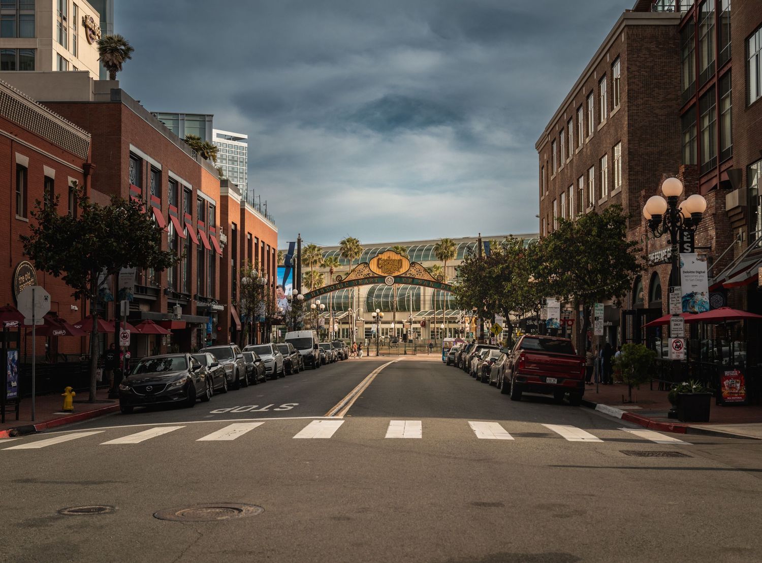 Downtown street with historic brick buildings and Petco Park stadium visible in the distance.