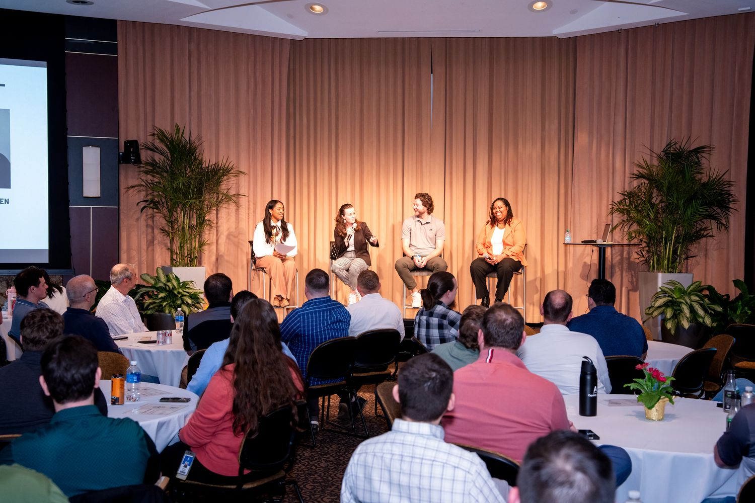 Panel of four speakers presenting to a full audience at the Amway GROW business celebration event.