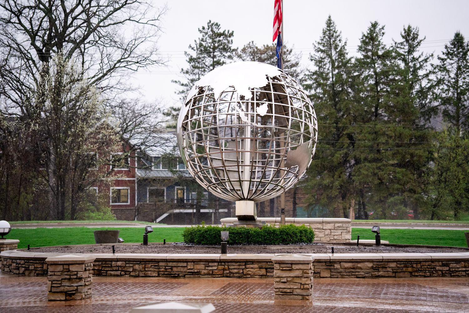 Large metallic globe sculpture landmark on a rainy day at the Amway corporate campus in Ada, Michigan.