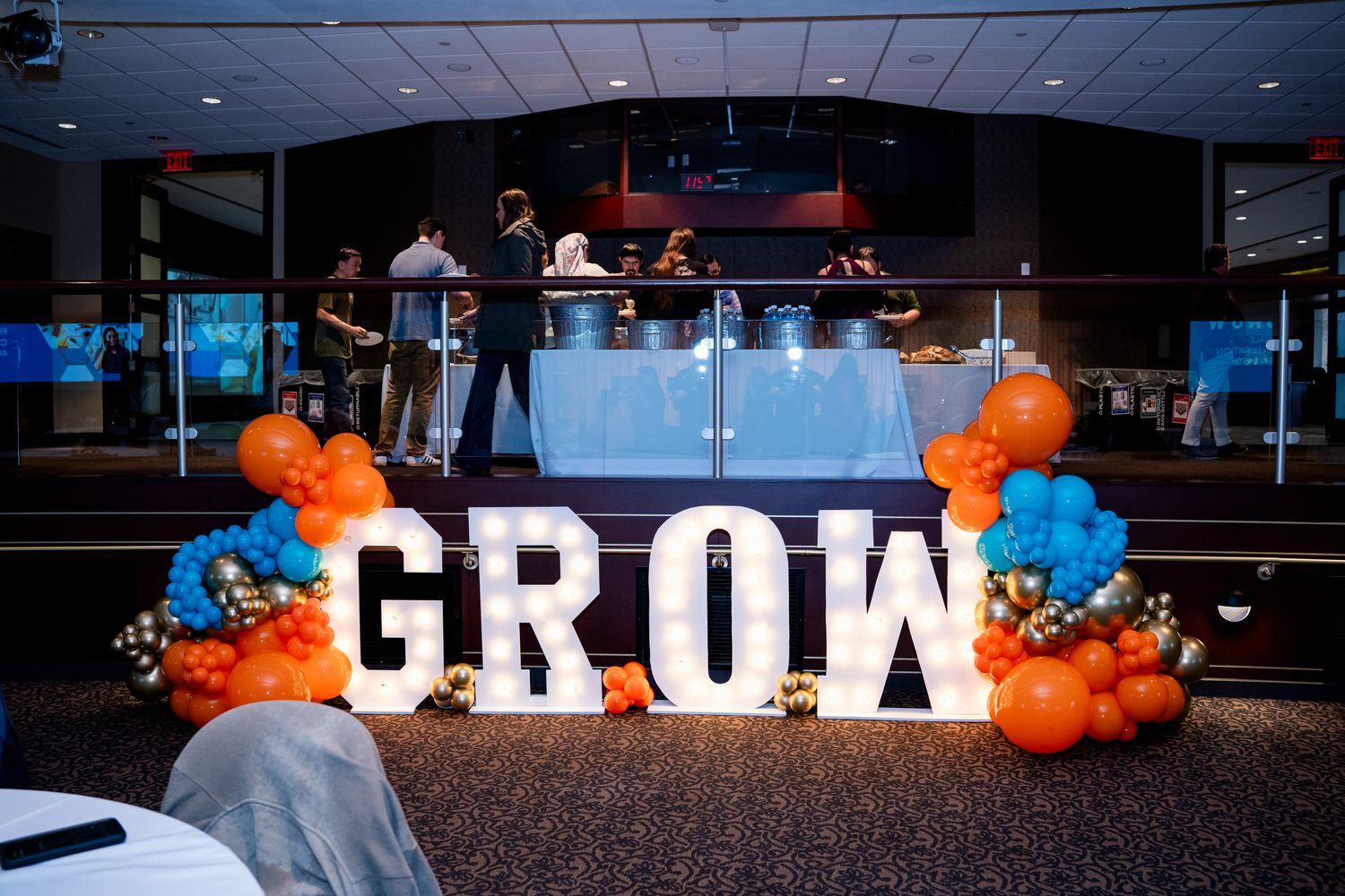Large illuminated GROW letter sign with orange and blue balloon decorations at an Amway celebration event.