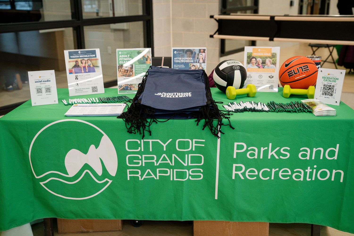A City of Grand Rapids Parks and Recreation display table with sports equipment and informational brochures.