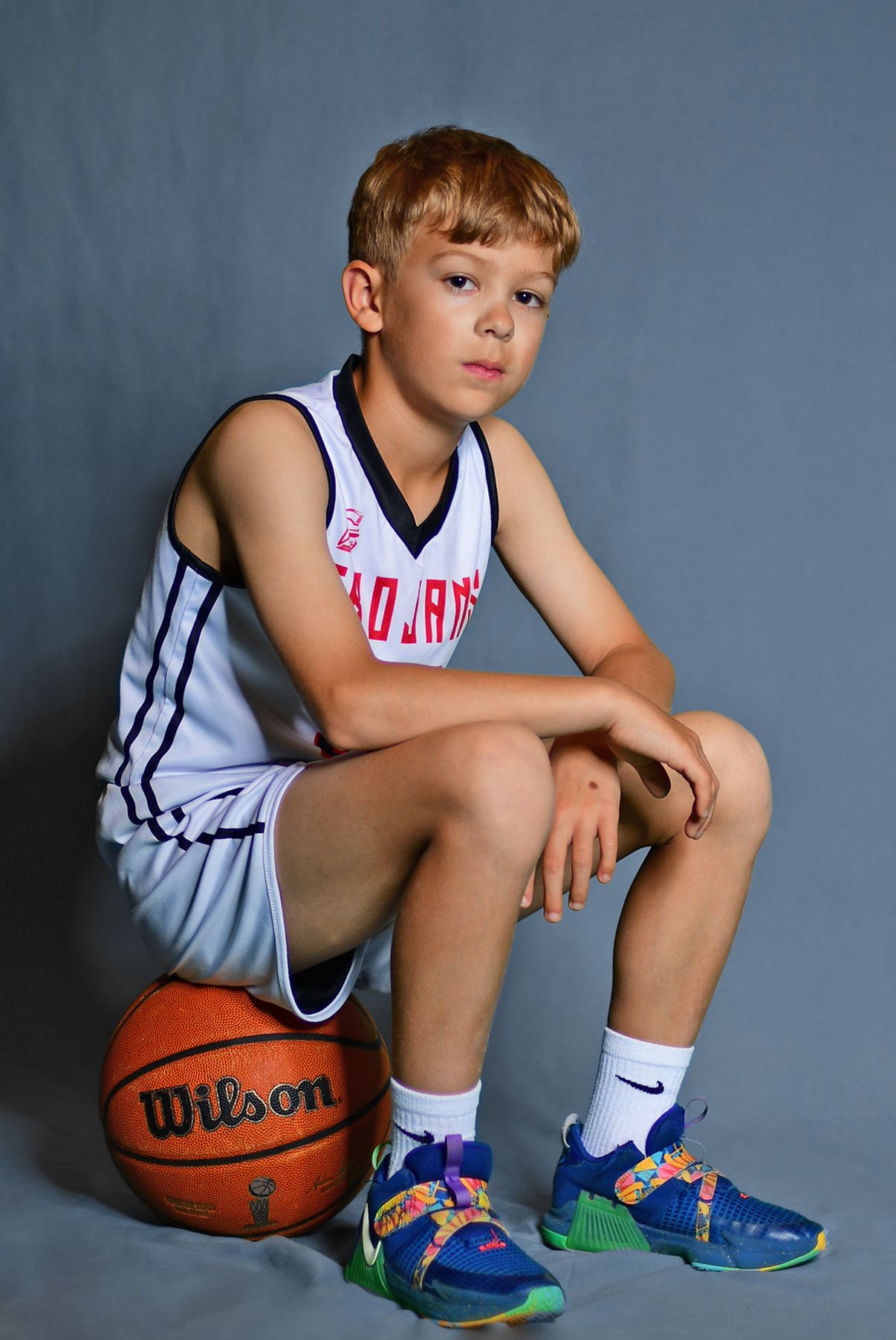 Male basketball player sitting on ball for portrait