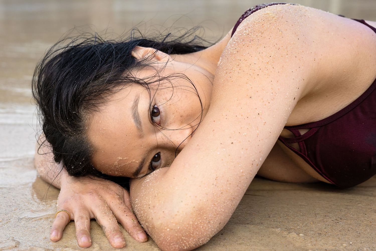 Woman in sleeveless top lying on the sand in different artistic poses.