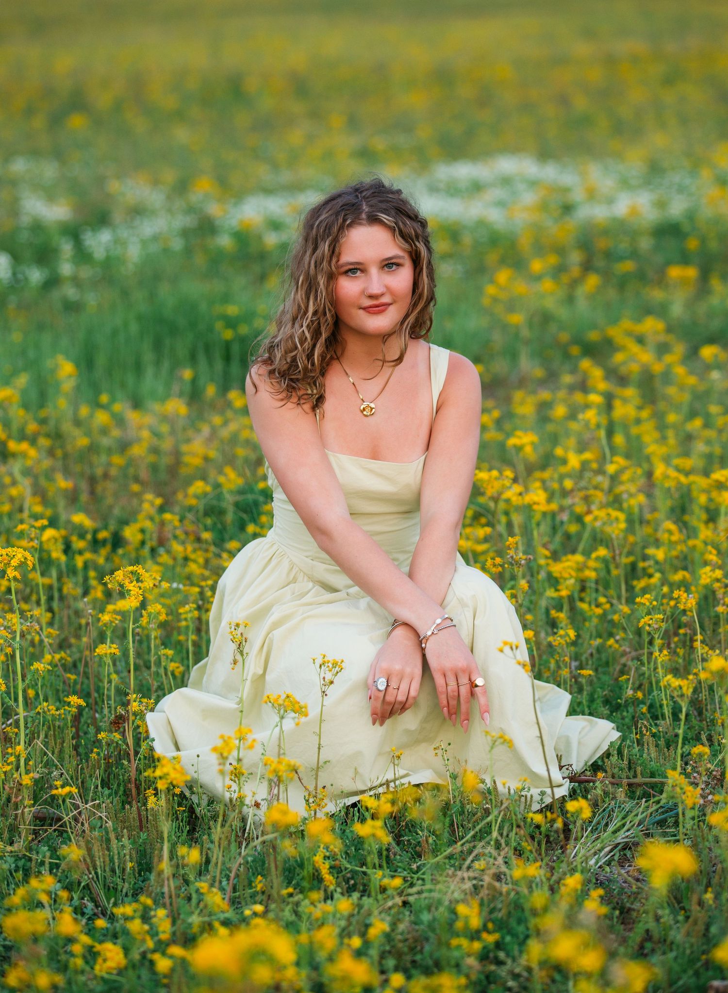A person in a yellow dress sits among vibrant wildflowers in a blooming meadow during spring.