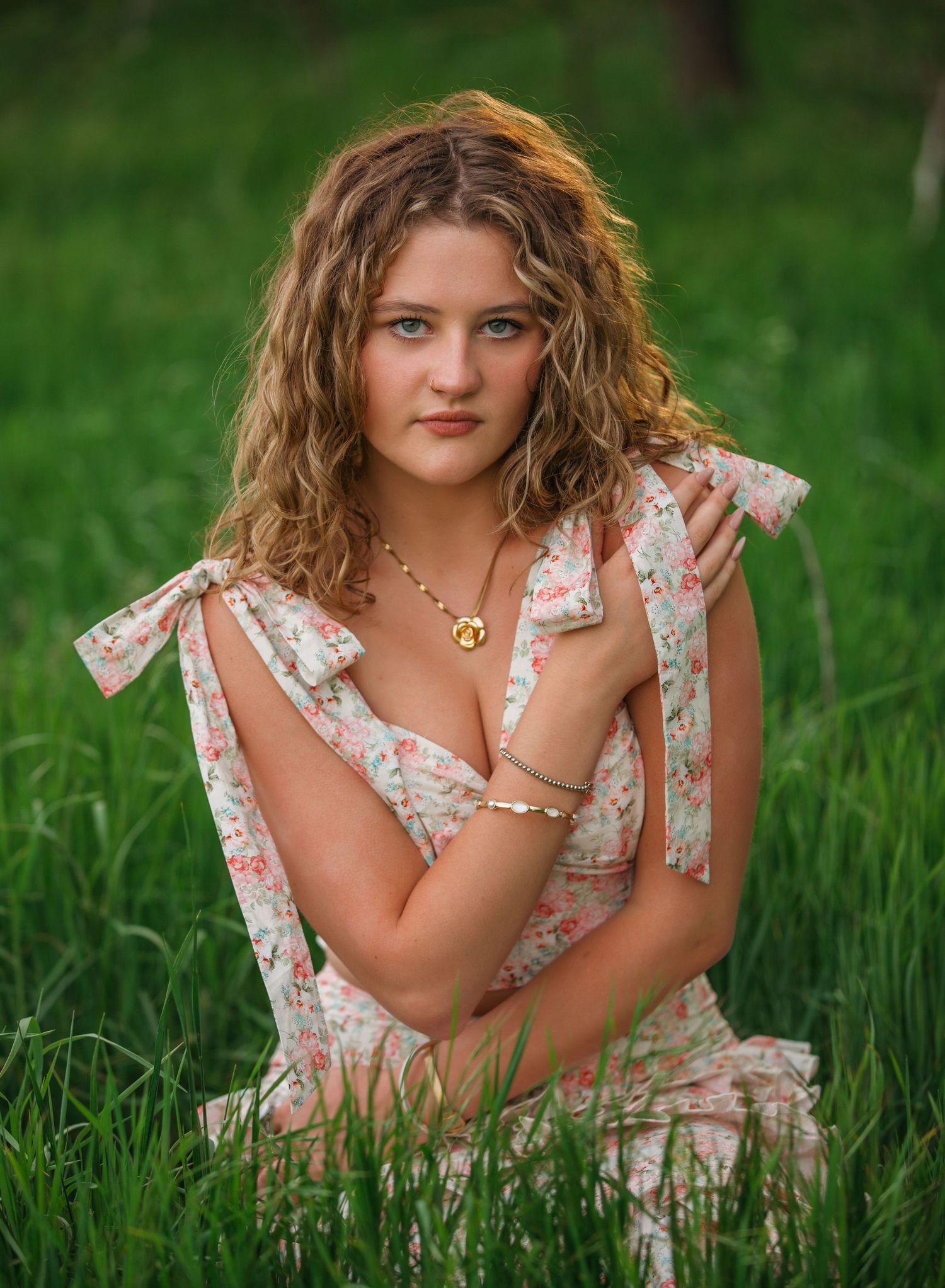 A Free-spirited person in a floral dress poses gracefully while laying in a lush green meadow during a summer day.