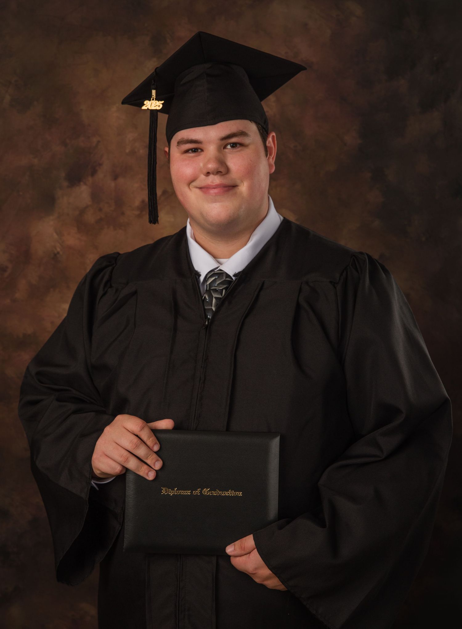 Graduate in traditional academic regalia displays diploma while posing for professional photos.