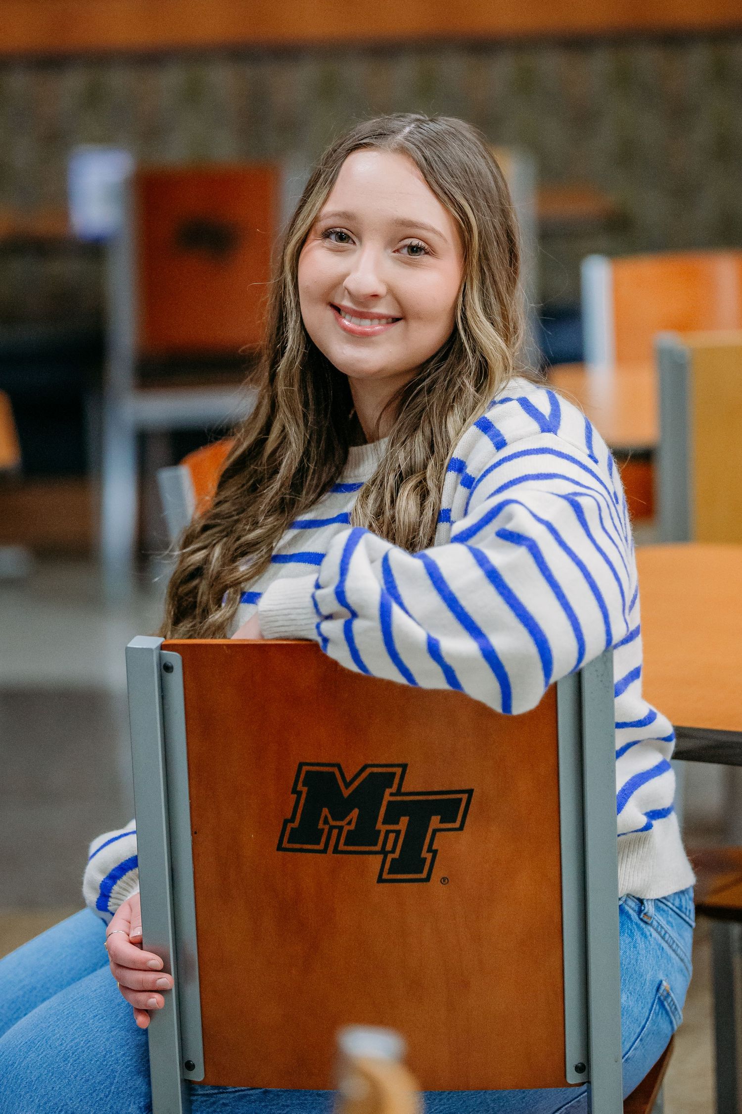 A portrait series showing someone seated in brown chairs wearing a blue and white striped sweater with joyful expressions.