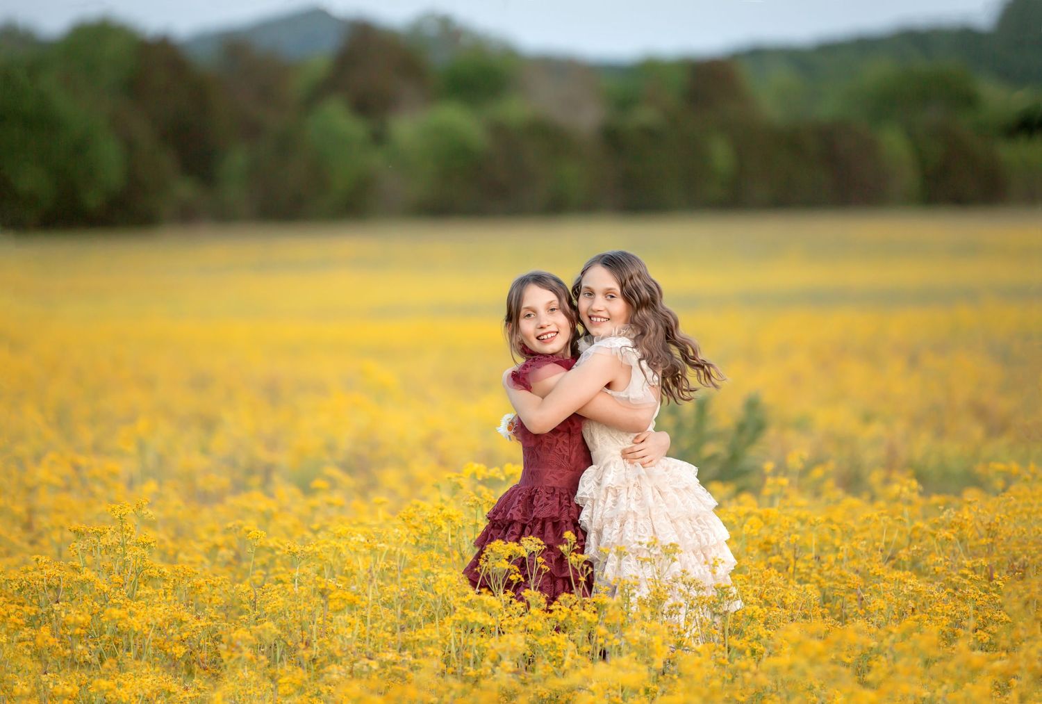 Two figures embrace while standing in a vibrant field of yellow wildflowers.