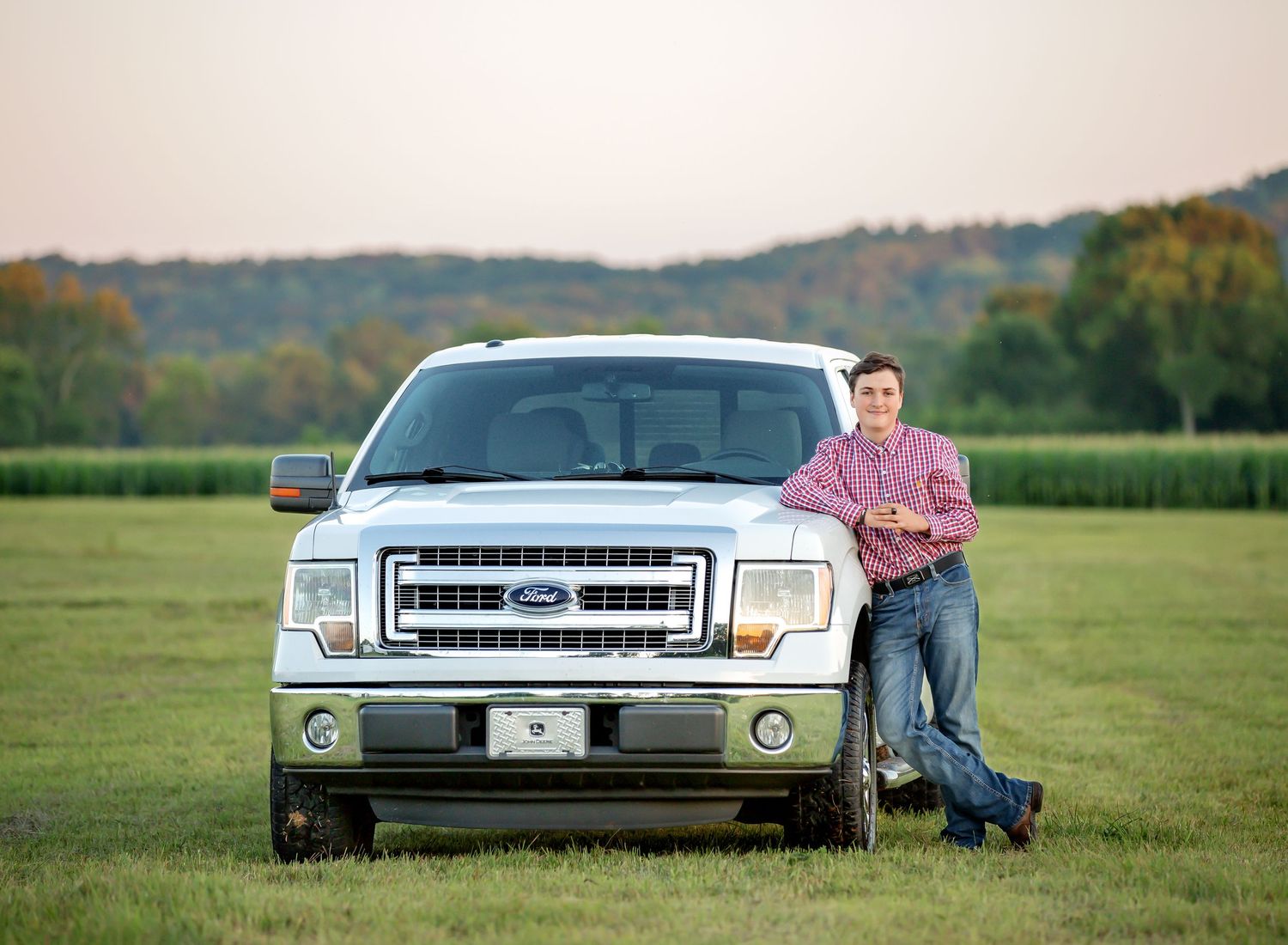 Casual portrait with Ford pickup truck in a rural field setting at sunset.
