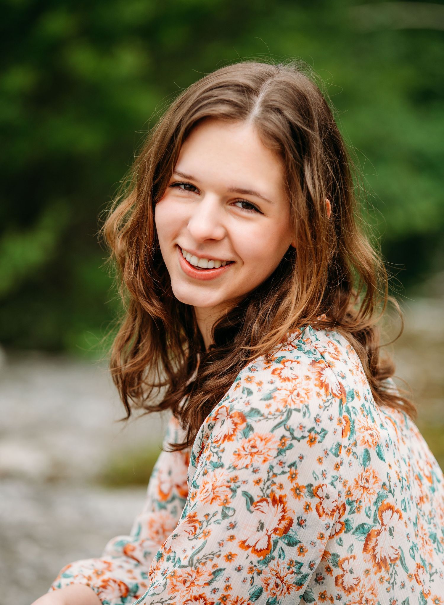 Outdoor portrait with floral print blouse against a natural green background.