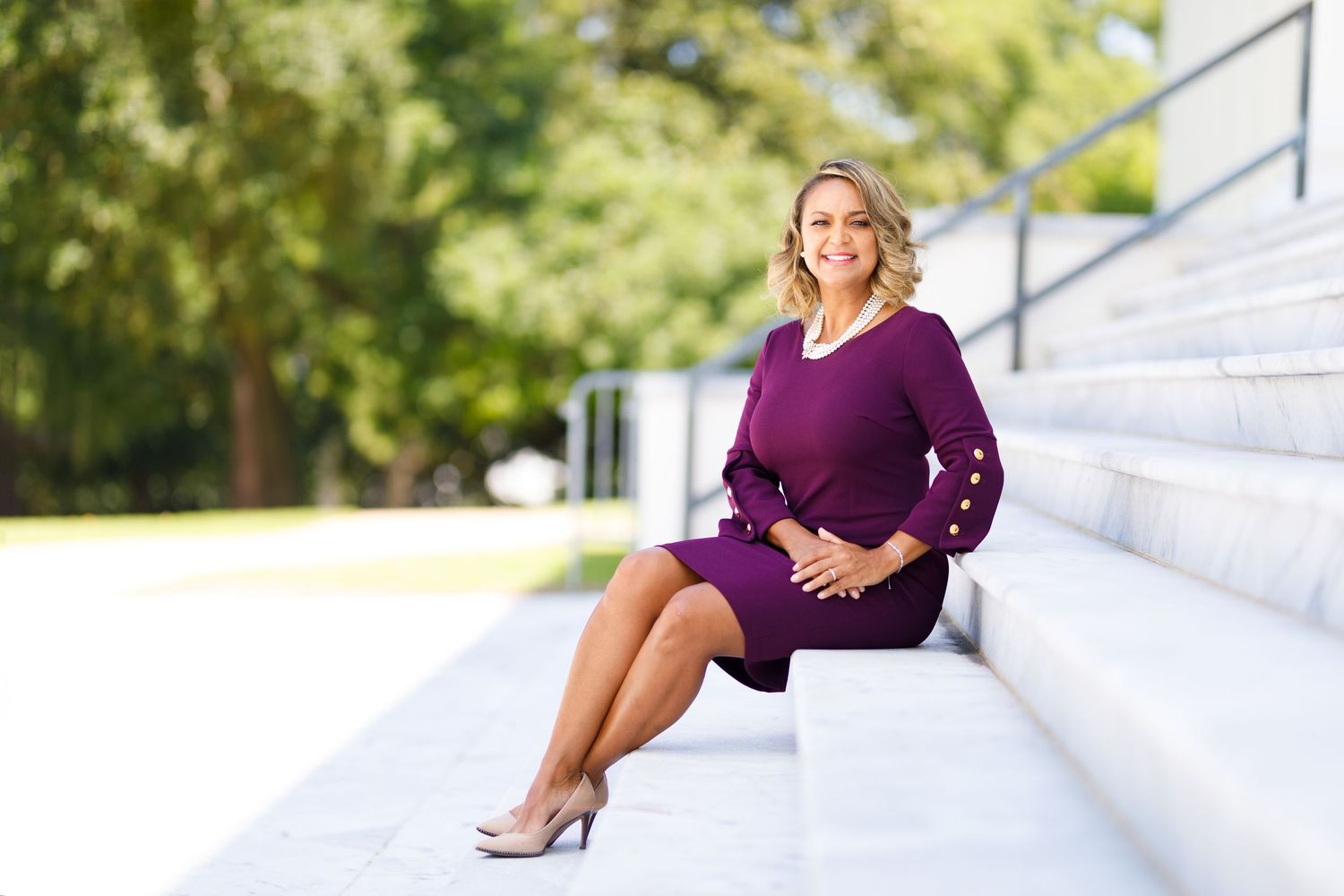 Professional modeling portrait session on white steps showcasing a purple dress and formal attire in natural lighting.