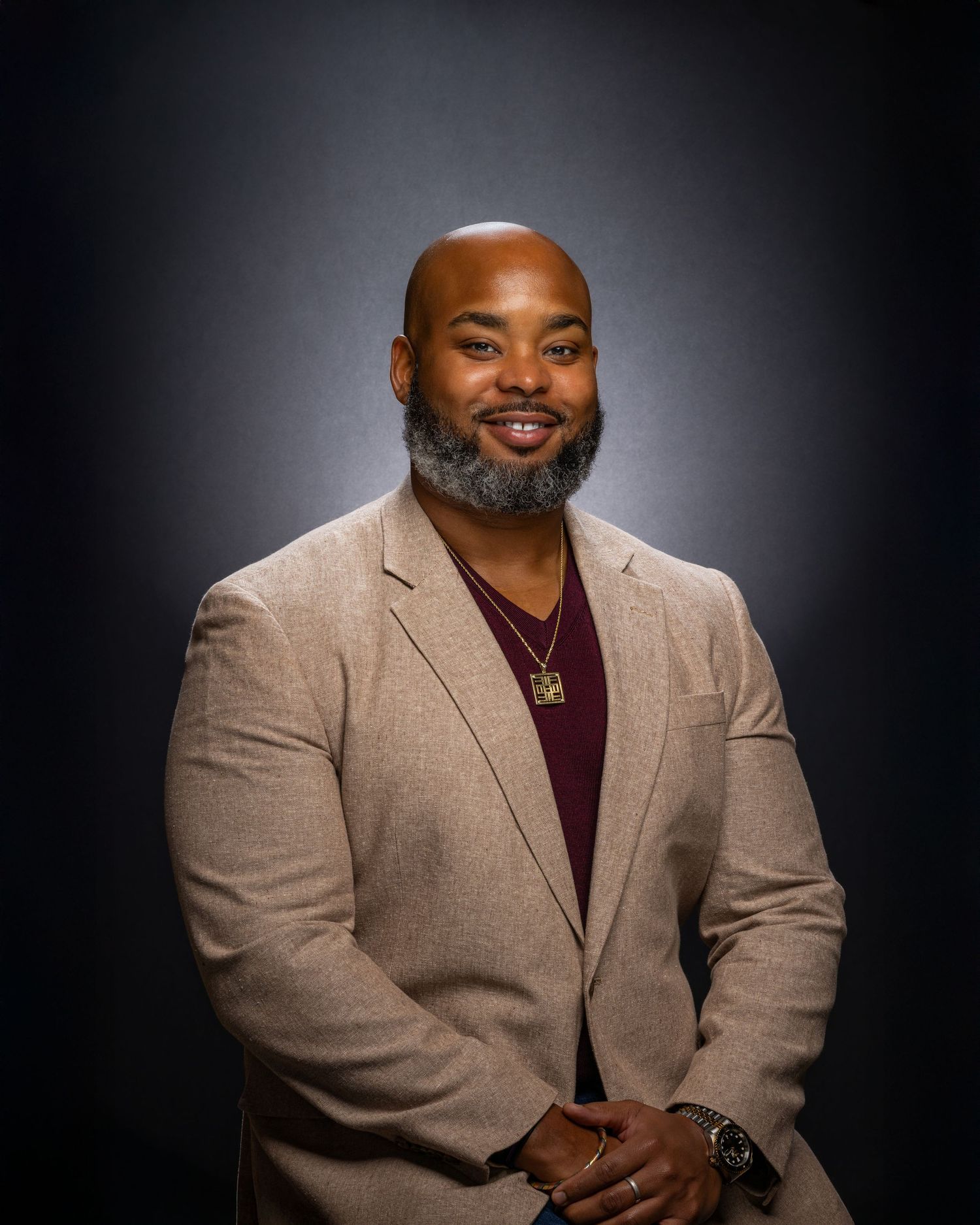 Professional portrait series in a beige blazer and burgundy shirt against dark background.