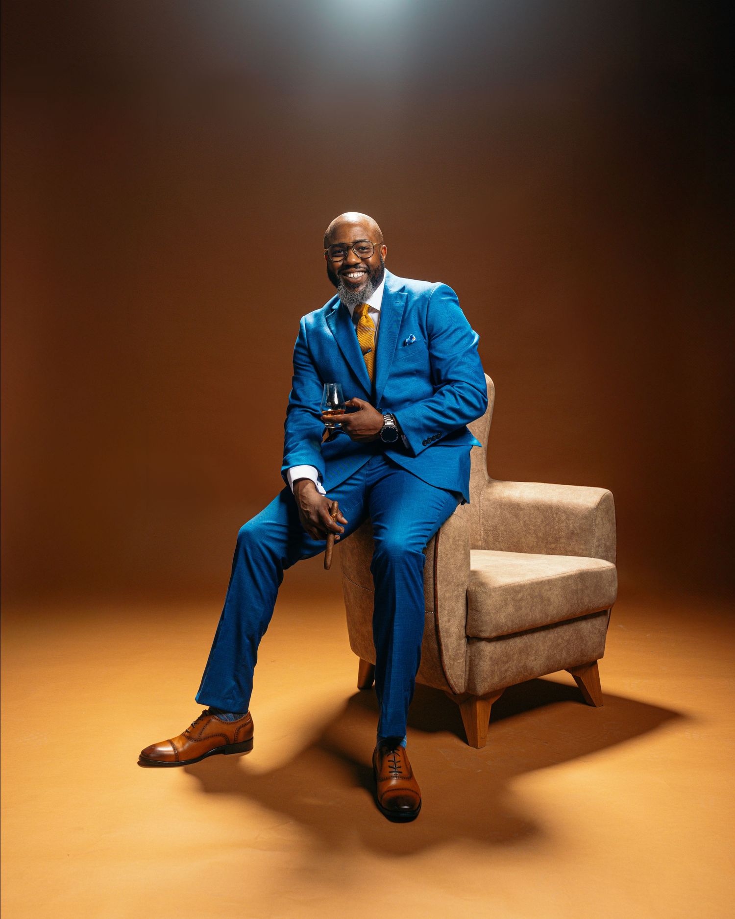 Dynamic poses of someone in a vibrant blue suit on an armchair with moody brown lighting.