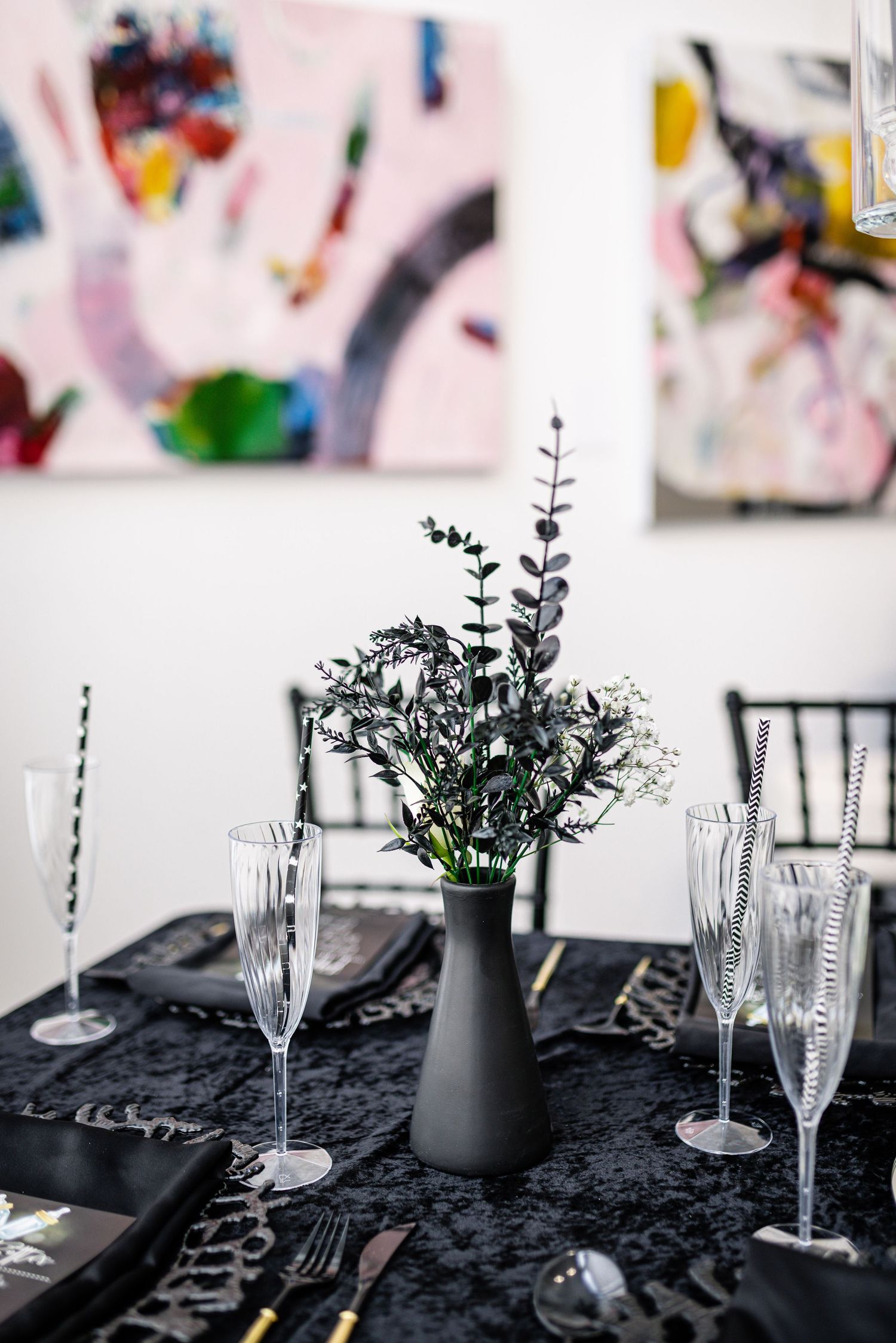 Elegant table setting with black tablecloth, champagne flutes and minimalist floral centerpiece.