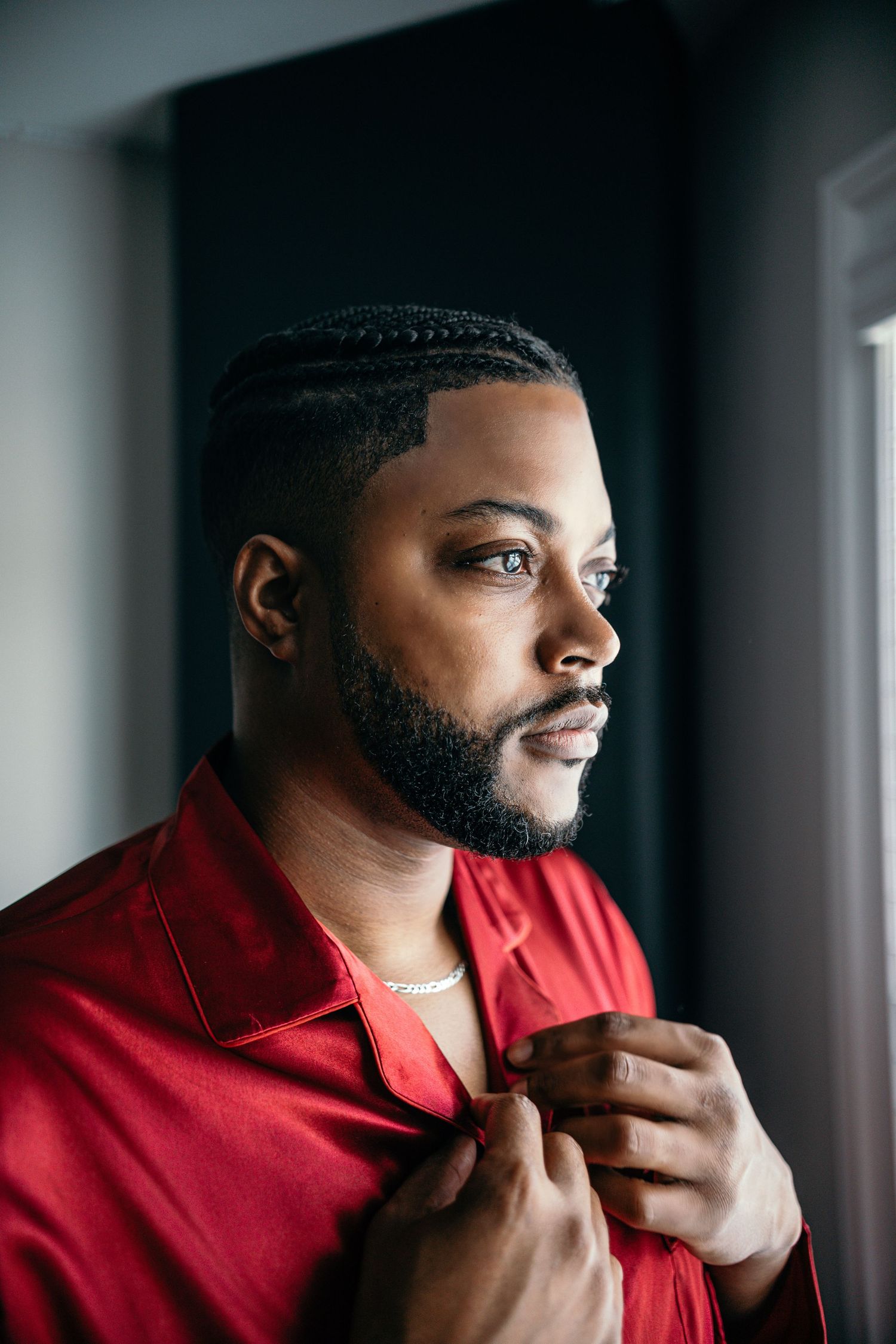 Portrait wearing red collared shirt against grey background in professional studio lighting.