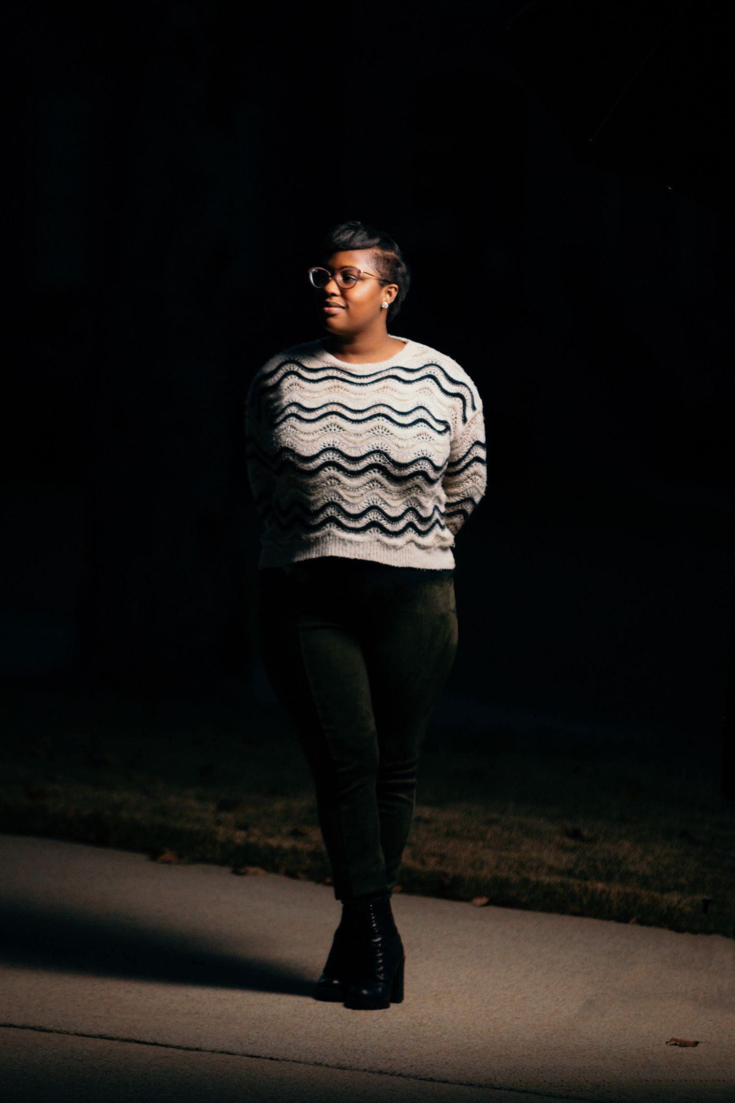 Dramatic black and white portrait in a chevron sweater against dark background.