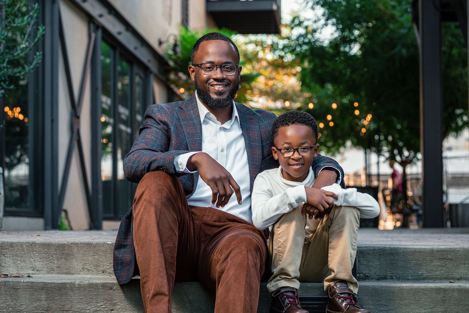 Professional photo of two people sitting on outdoor steps in business attire.