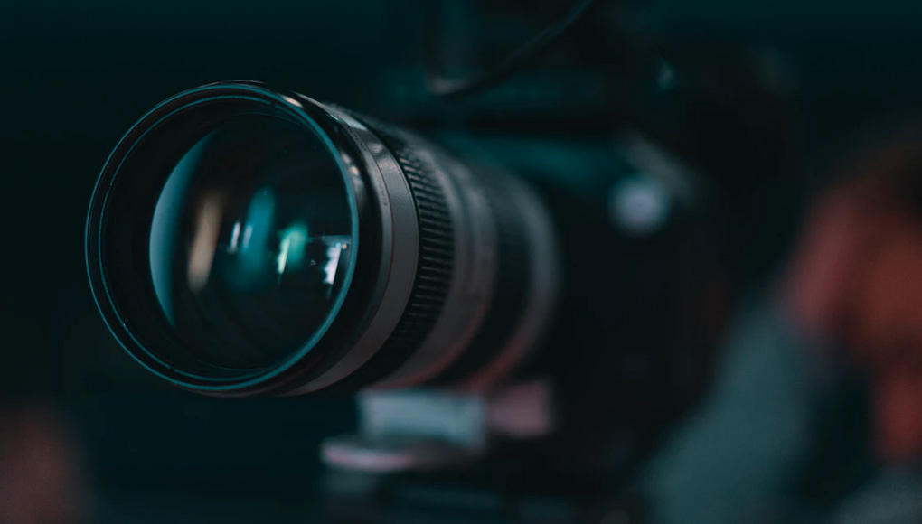 Close-up shot of a professional camera lens with teal highlights.