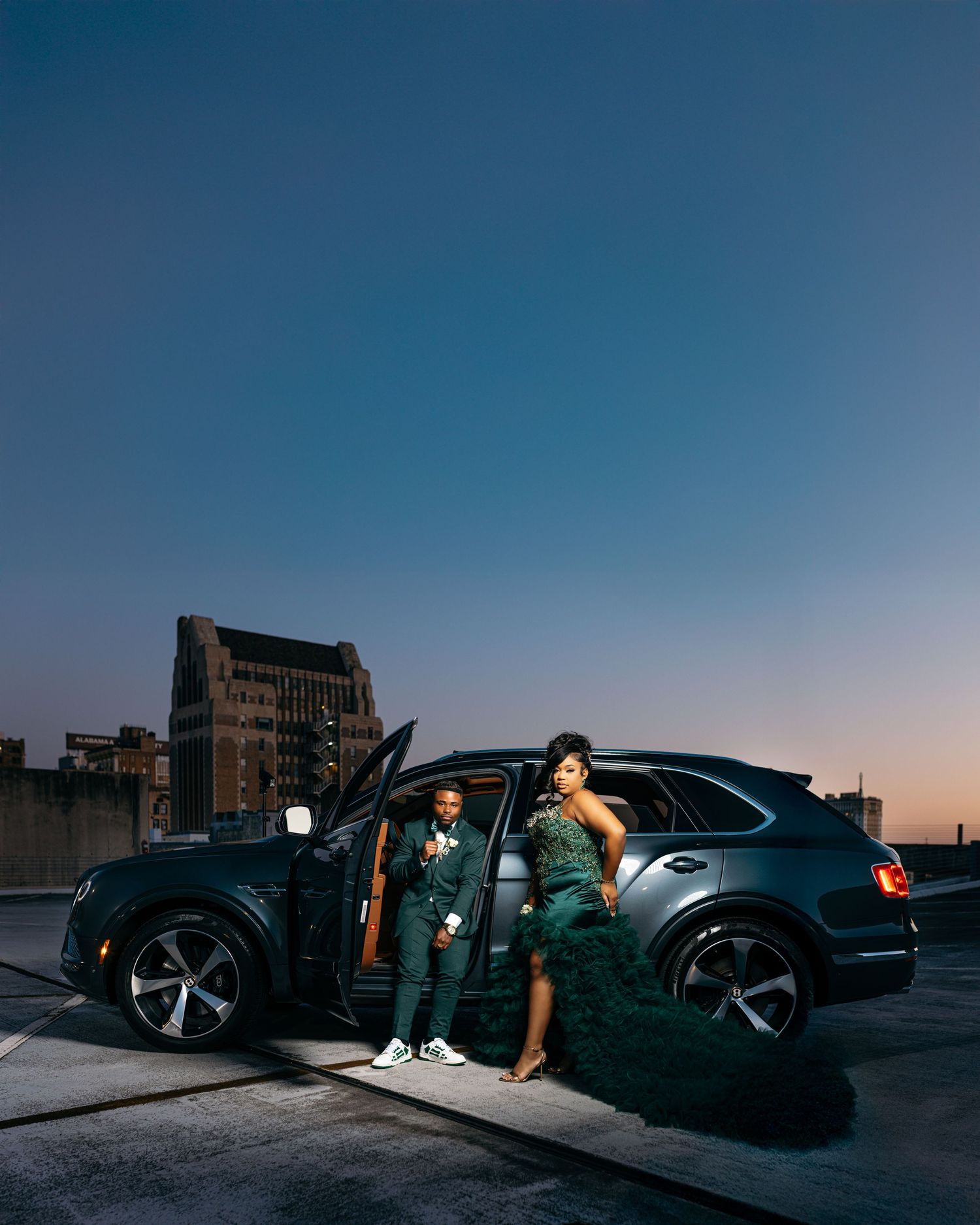 Dramatic nighttime photoshoot with luxury car and city skyline silhouette.