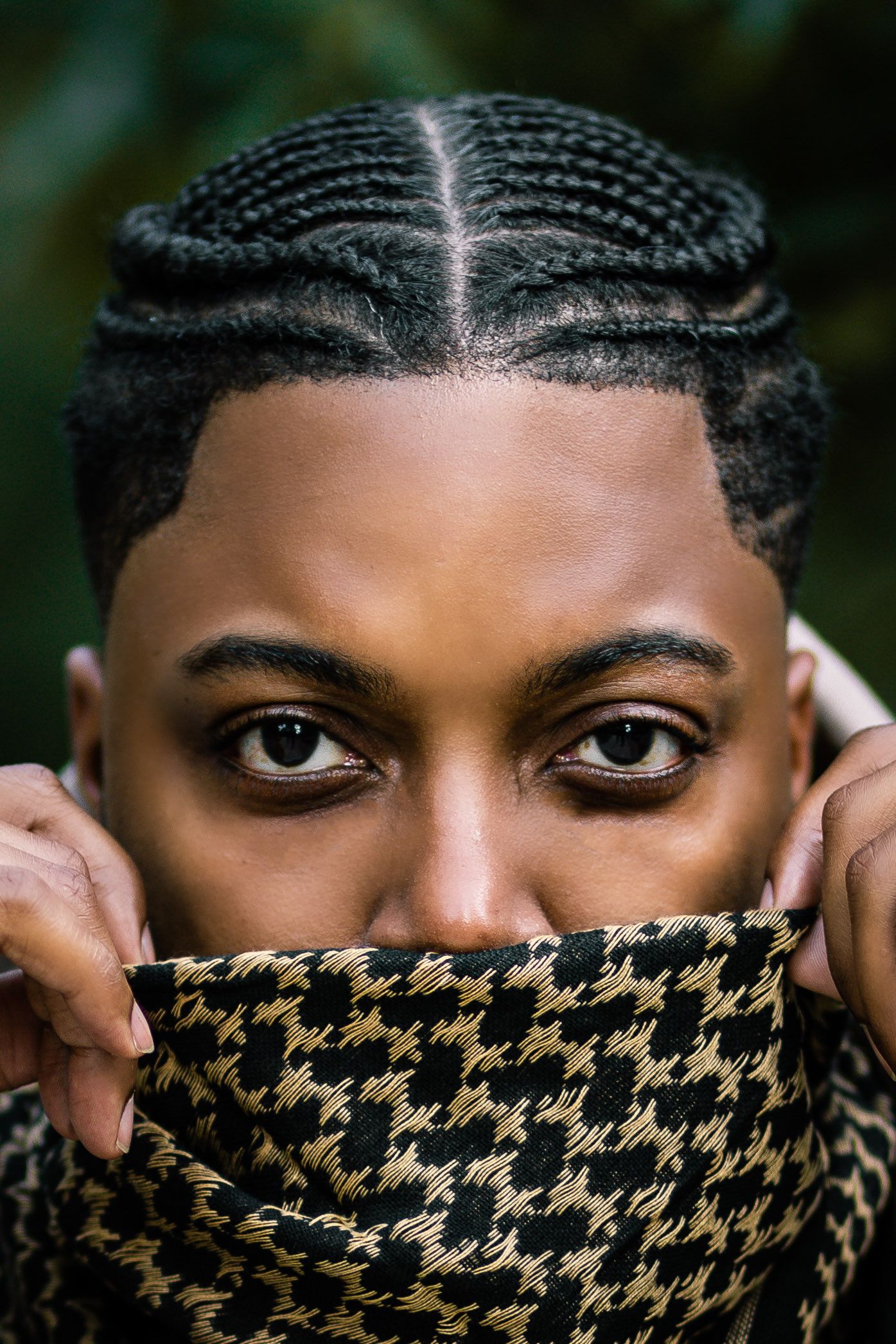 Close-up detail of braided hairstyle with houndstooth pattern face covering.
