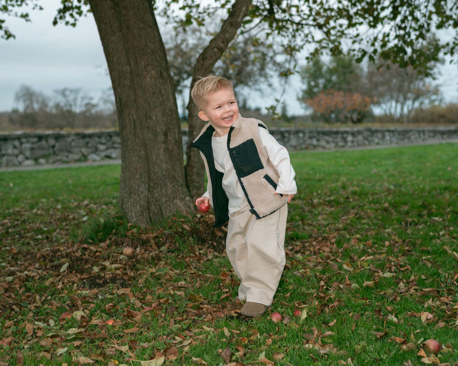 A playful sequence of someone running through fallen autumn leaves in a park.