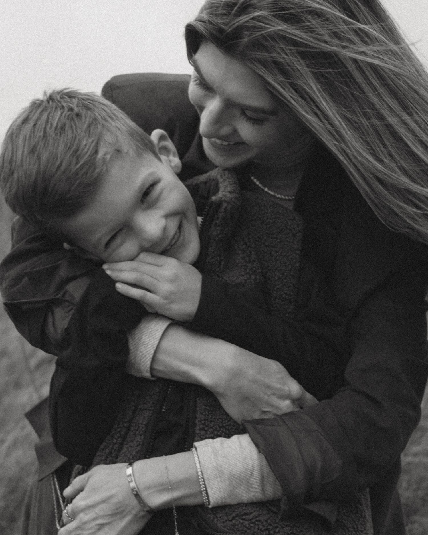 Intimate black and white portrait of family members sharing an affectionate moment outdoors.