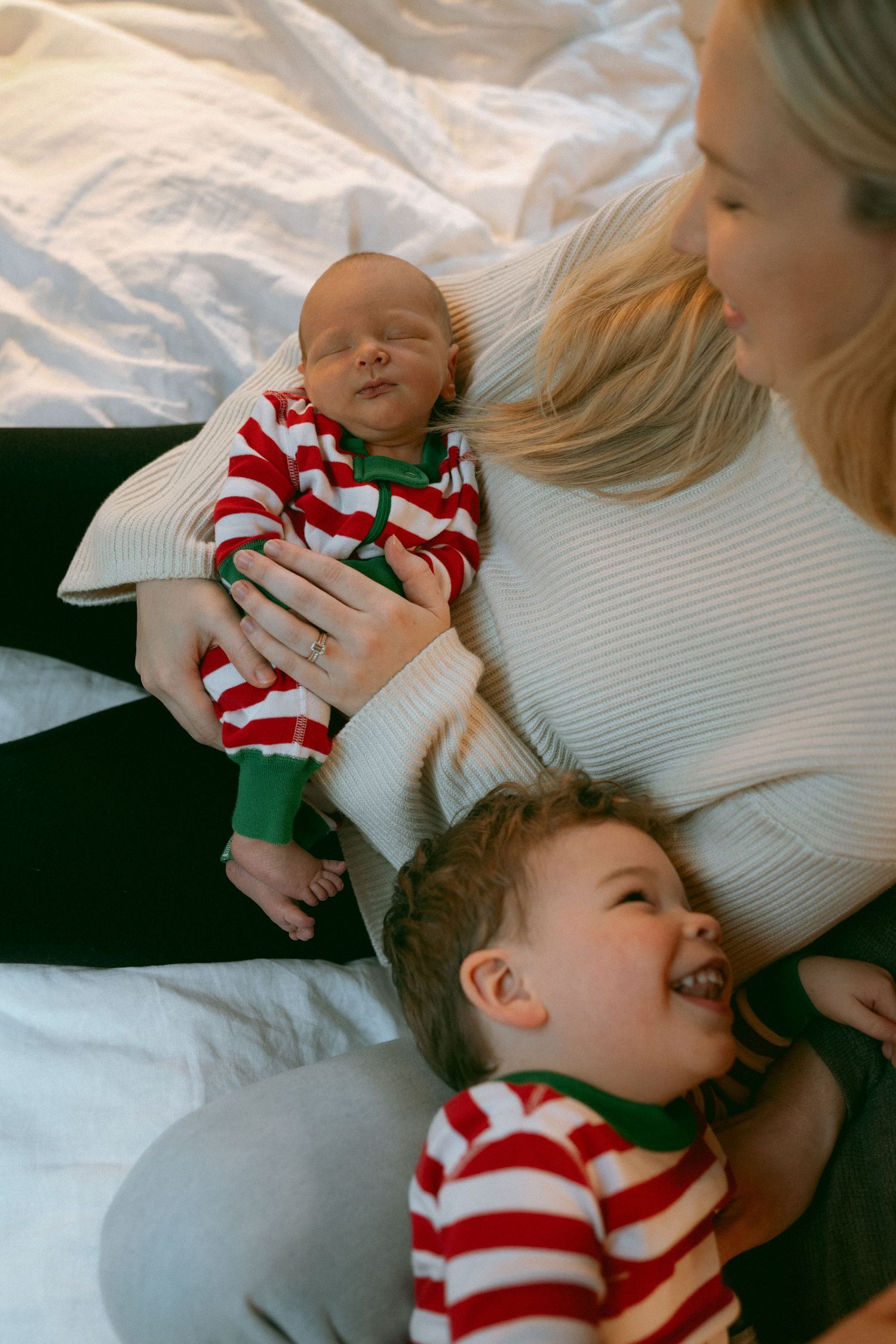 Four candid photos showing tender moments between parent and child wearing matching red and white striped holiday outfits.