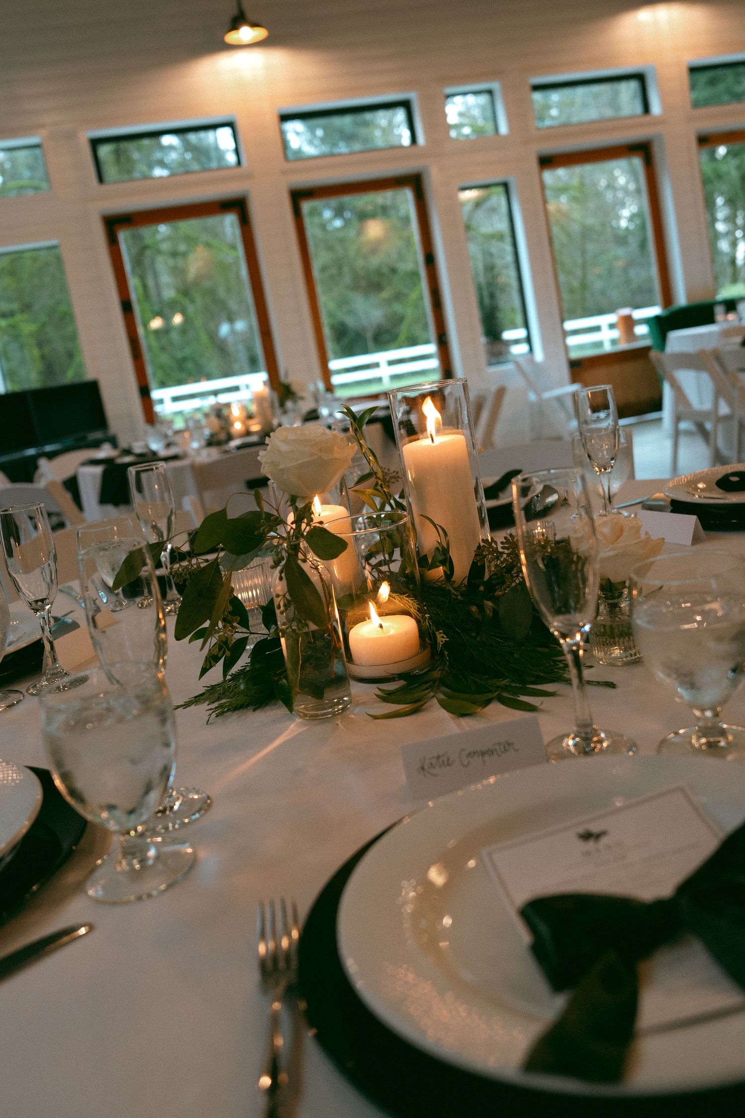 Elegant wedding reception table with candlelight and greenery centerpieces.