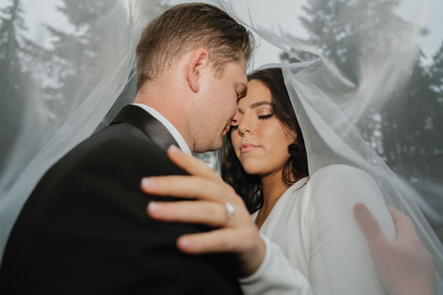 Intimate wedding portrait captured against a misty forest backdrop.