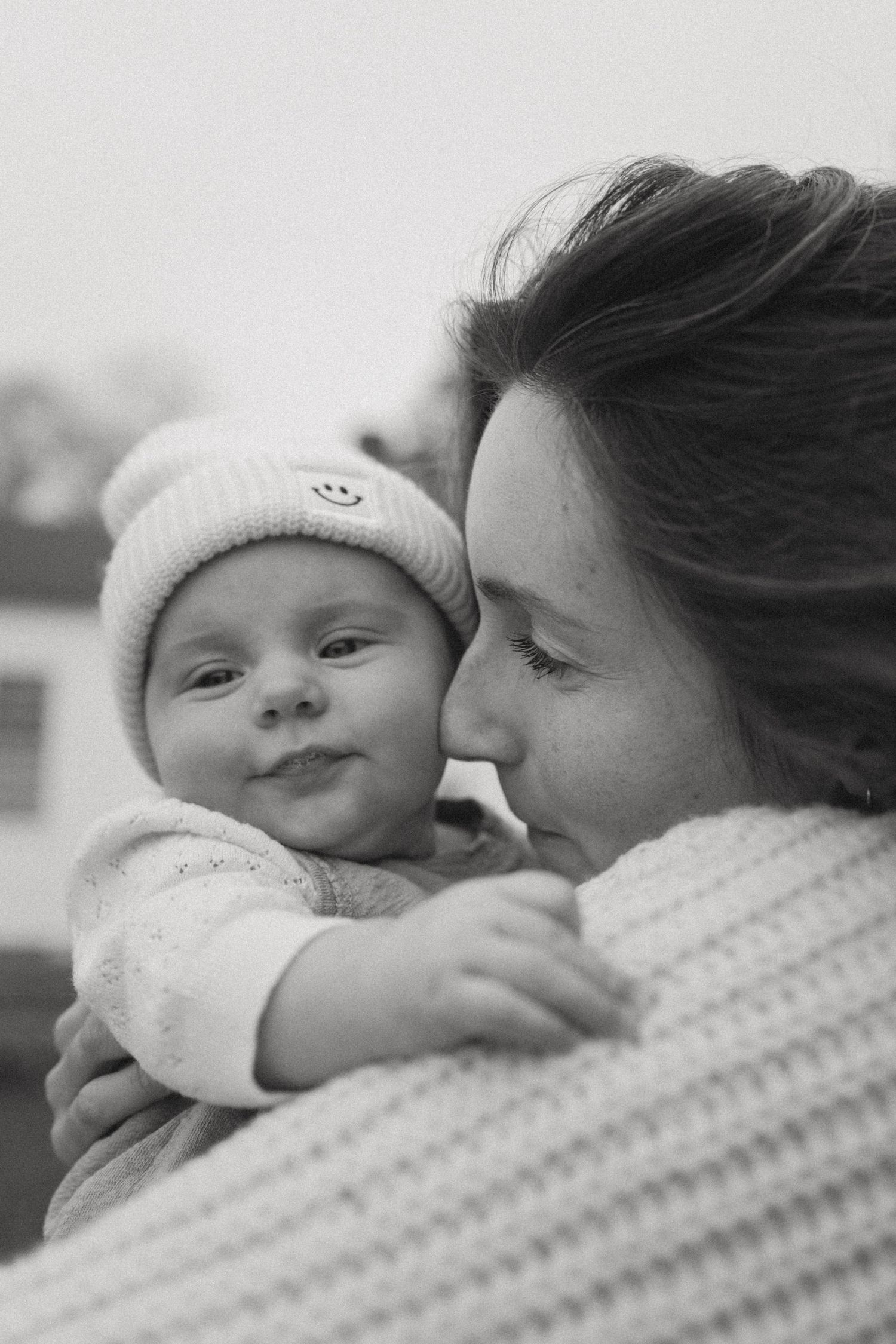 A tender black and white photo series showing a parent sharing intimate moments with their newborn baby.