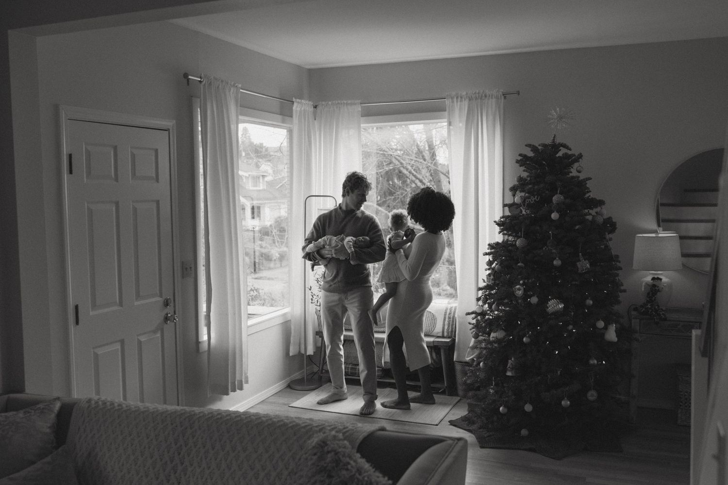 Black and white photo sequence showing a Christmas tree being set up in a living room near a window.