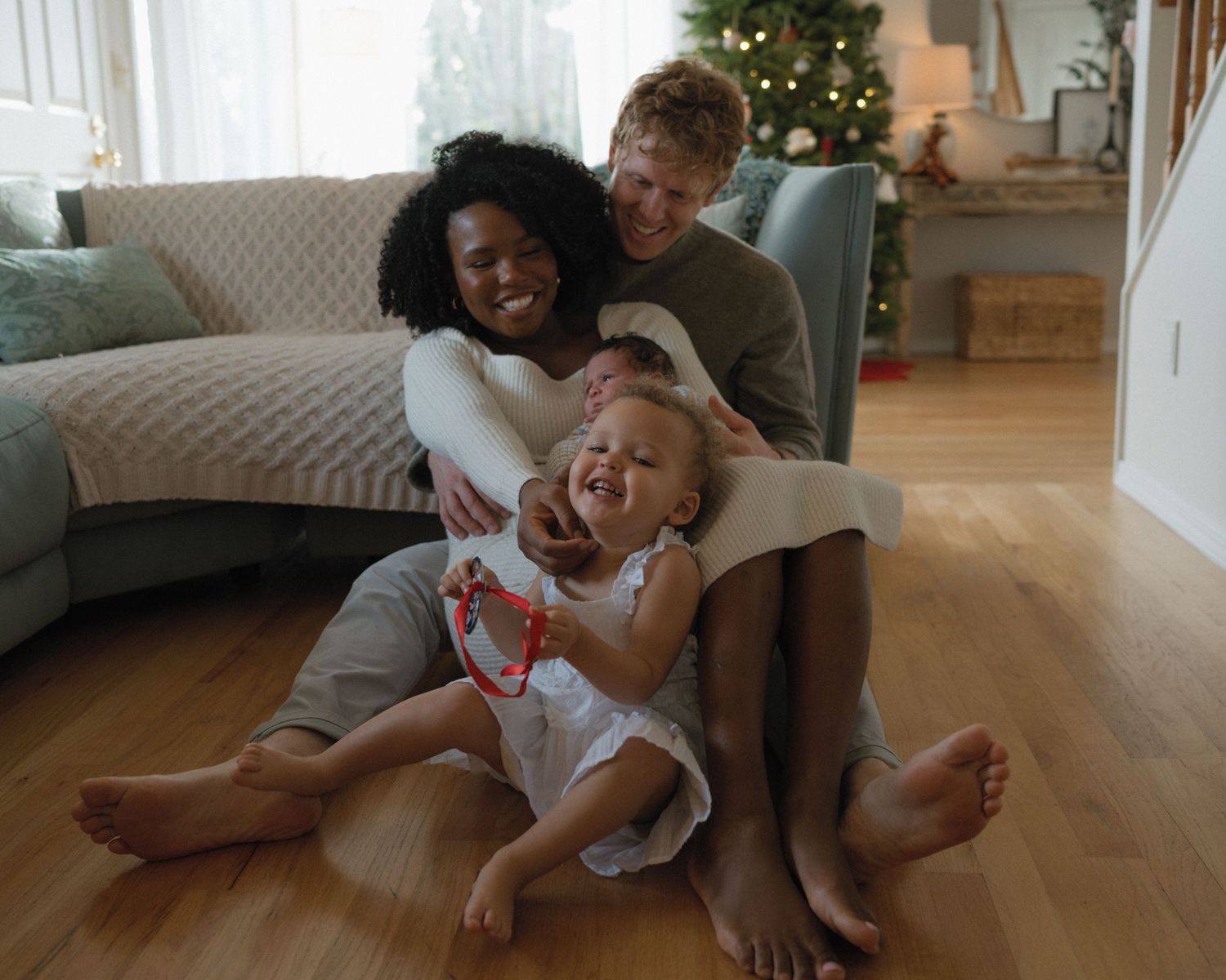 A playful sequence of family moments captured on a living room floor with a decorated Christmas tree in the background.
