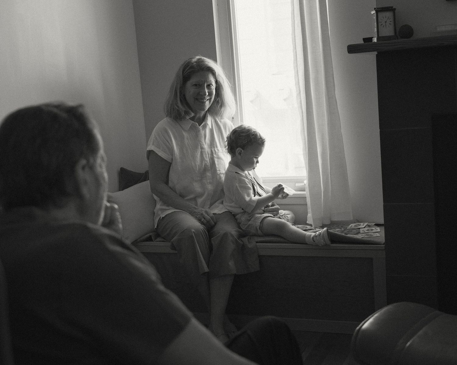 Black and white photo series showing a quiet interior scene with figures seated by a window.