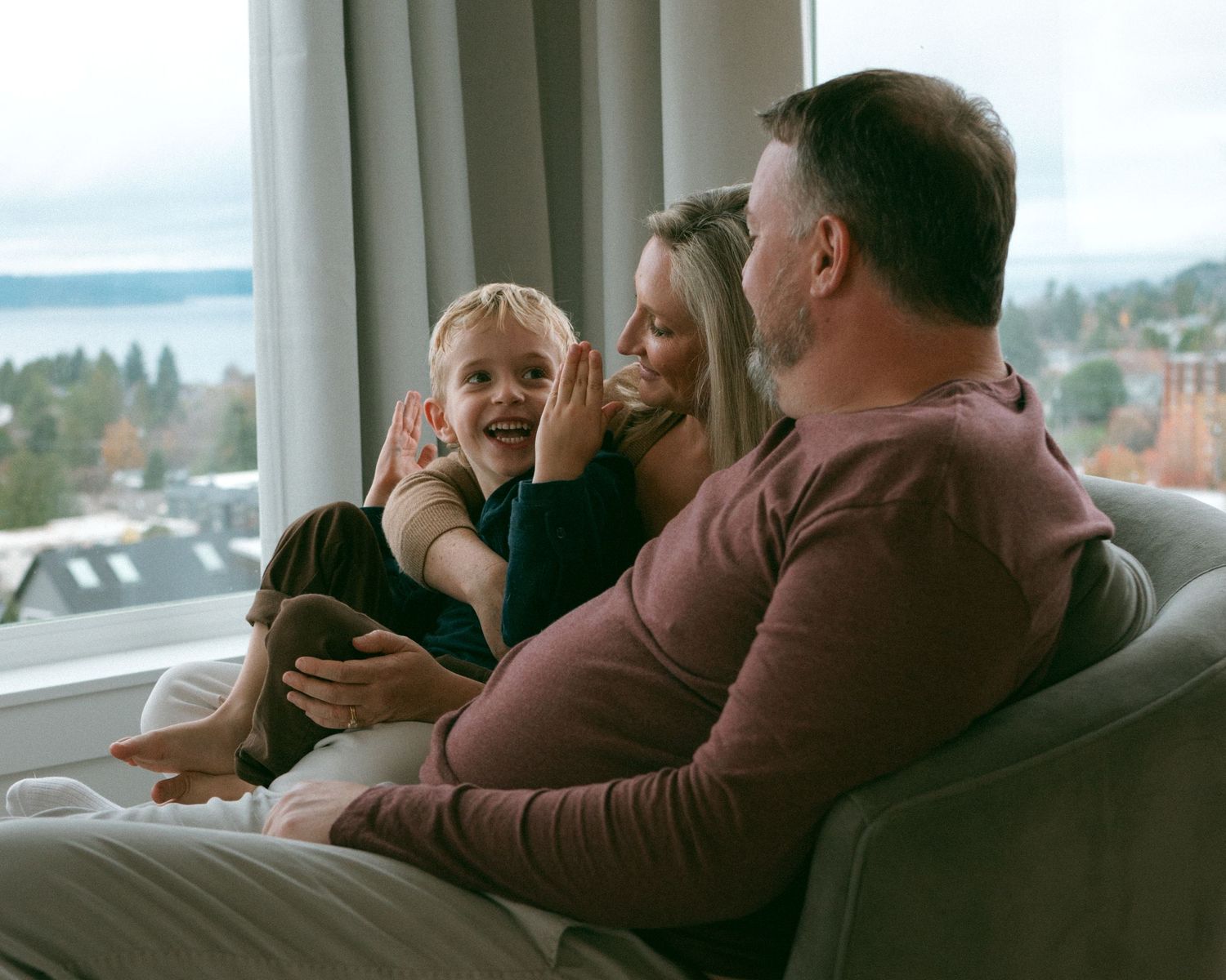 Cozy family moments captured on a sofa with natural window light.
