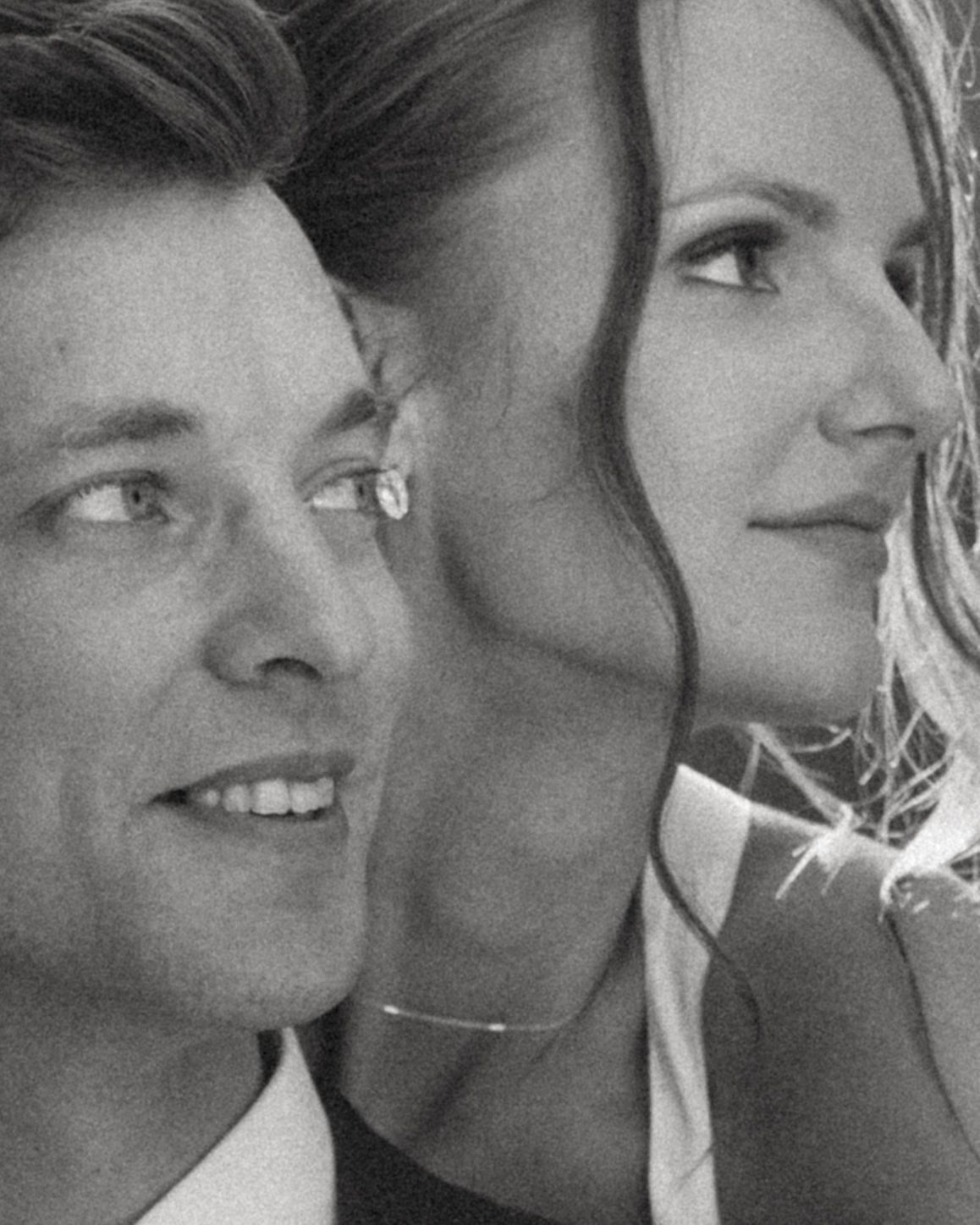 Black and white close-up portrait of a smiling man and a woman in profile, looking off into the distance together.
