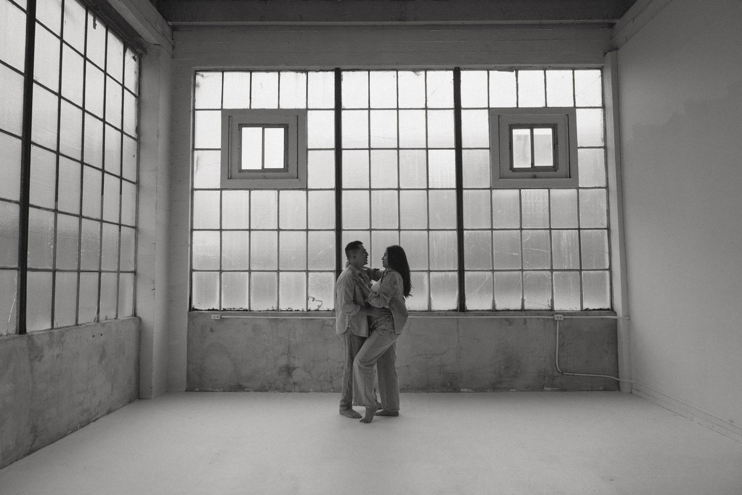Industrial loft space with large windows creating dramatic lighting.