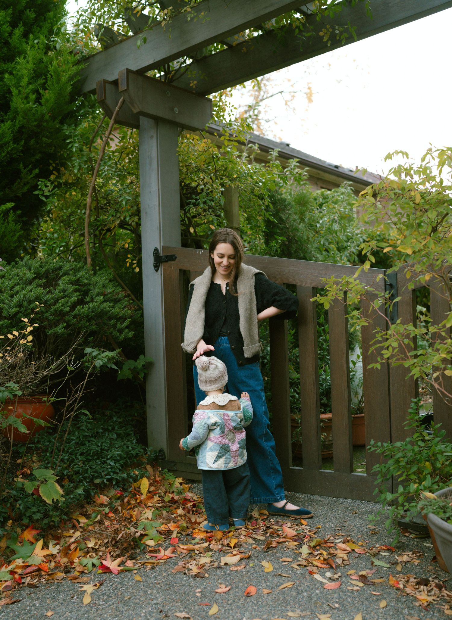 A wooden garden gate surrounded by autumn foliage and greenery.