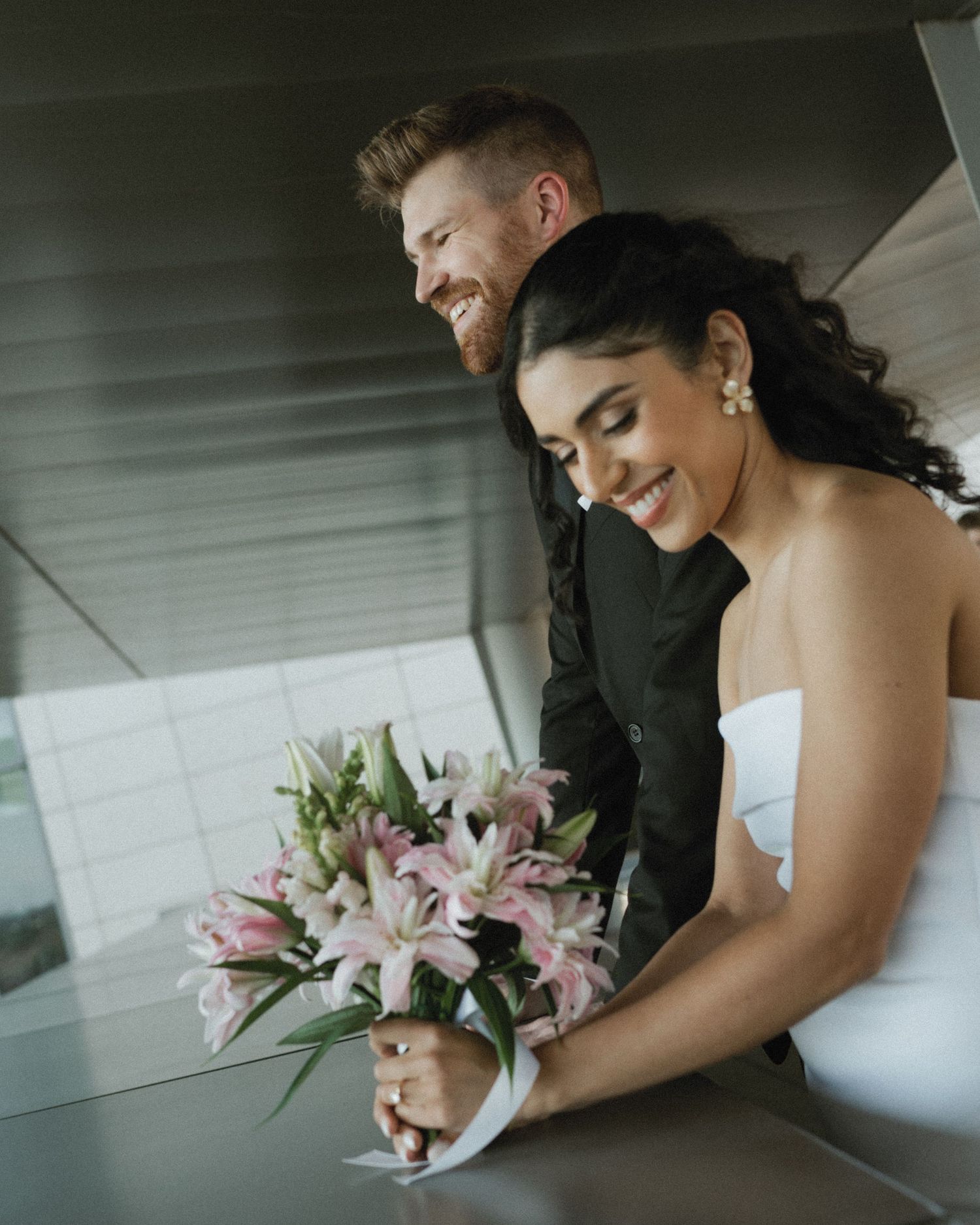 A tender moment shared with pink lily bouquet during wedding preparations.