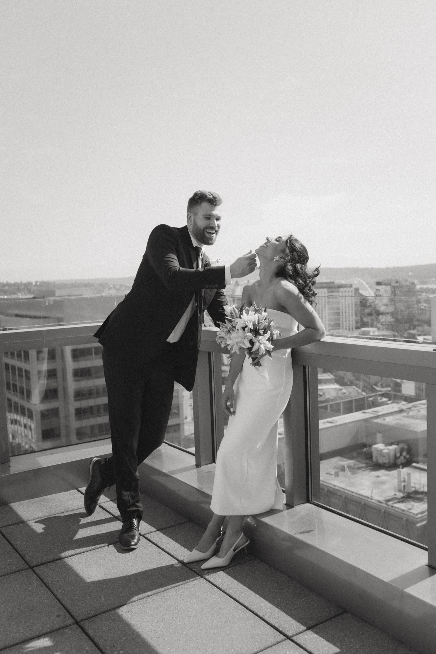 A playful wedding moment captured on a rooftop with city views.