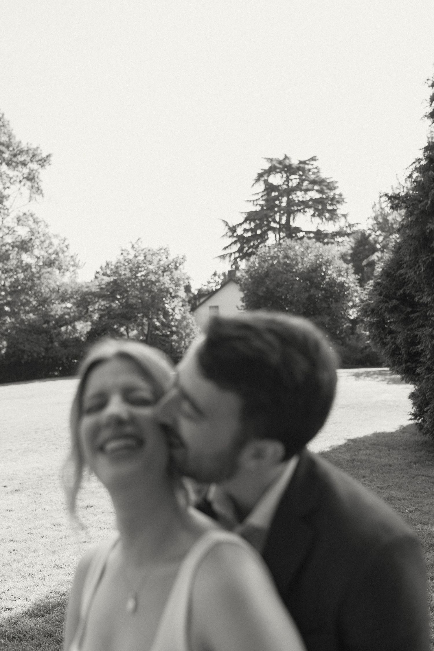 A candid black and white photo capturing a joyful moment between newlyweds outdoors.